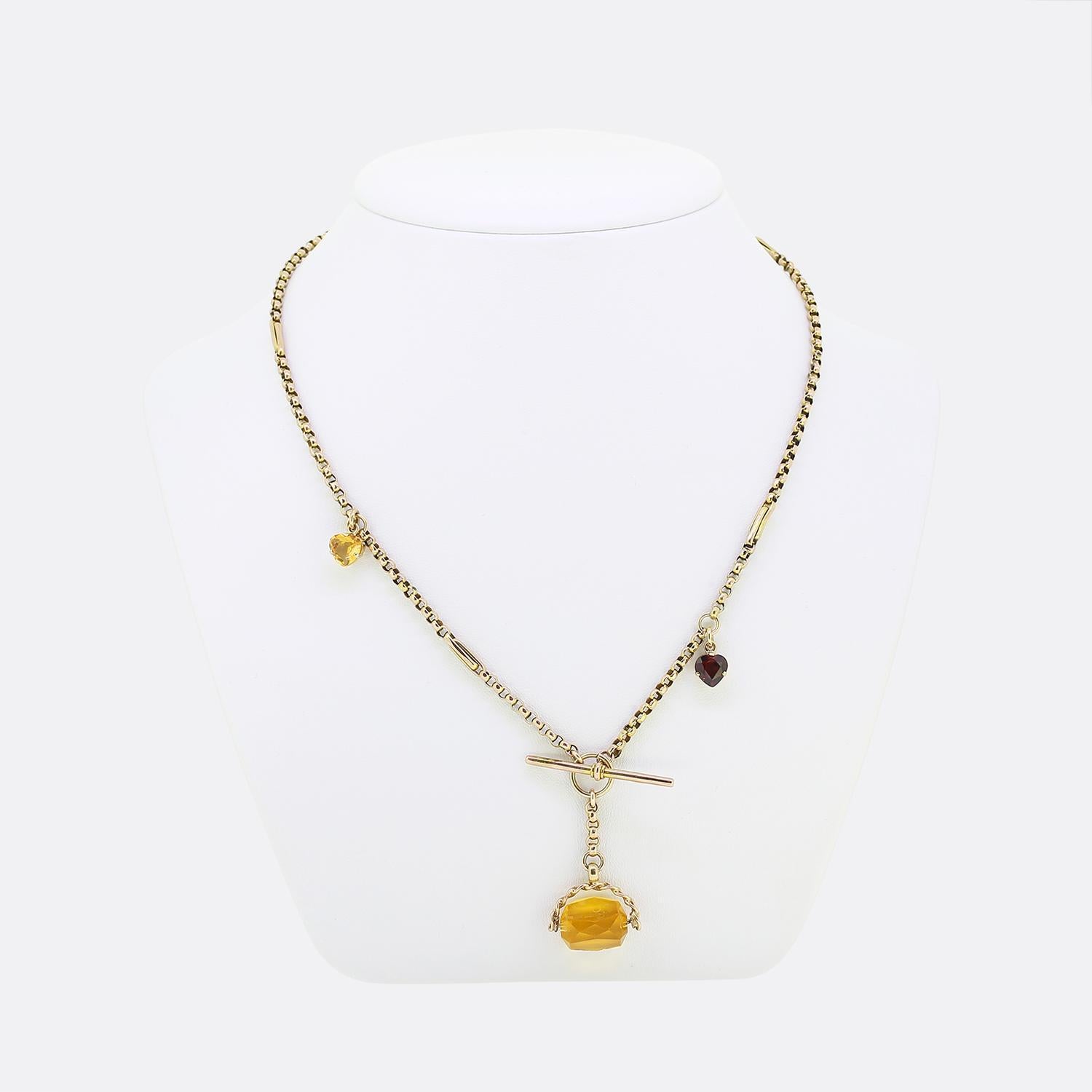 Here we have a beautiful multi gemstone charm necklace. A 9ct yellow gold chain with a T bar fastening focally suspends a large citrine set fob which freely spins at the wearers discretion. This principal stone is then accompanied by a duo of heart