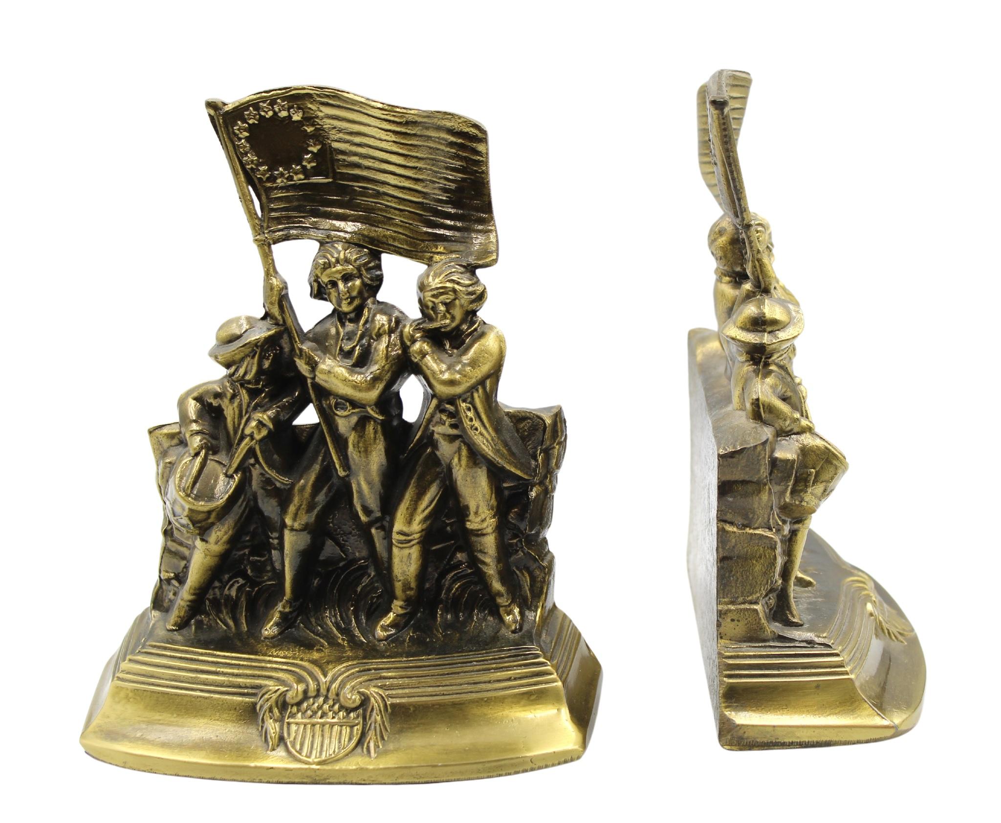 Offered is a set of vintage brass Revolutionary War soldiers bookends. Each bookend depicts a fife player, a drummer, and a flag bearer, marching in step together across a grassy field. The flag bearer hoists a large 13-star medallion flag into the
