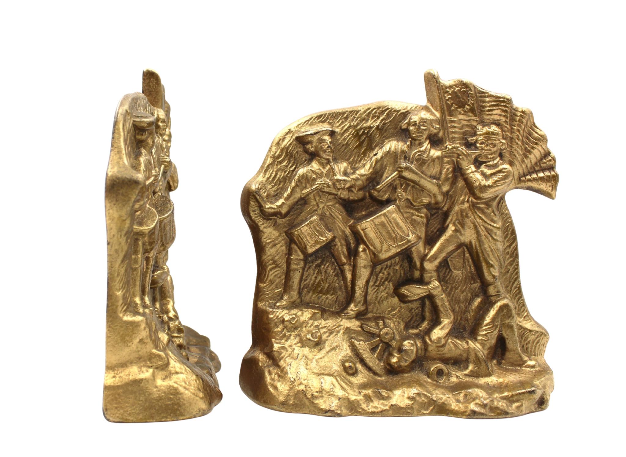 In offerta un set di fermalibri d'epoca in ottone con soldati della Guerra Rivoluzionaria. Ogni fermalibri raffigura un suonatore di piffero e due tamburini che marciano al passo su un campo di battaglia erboso. Uno dei batteristi è anche un