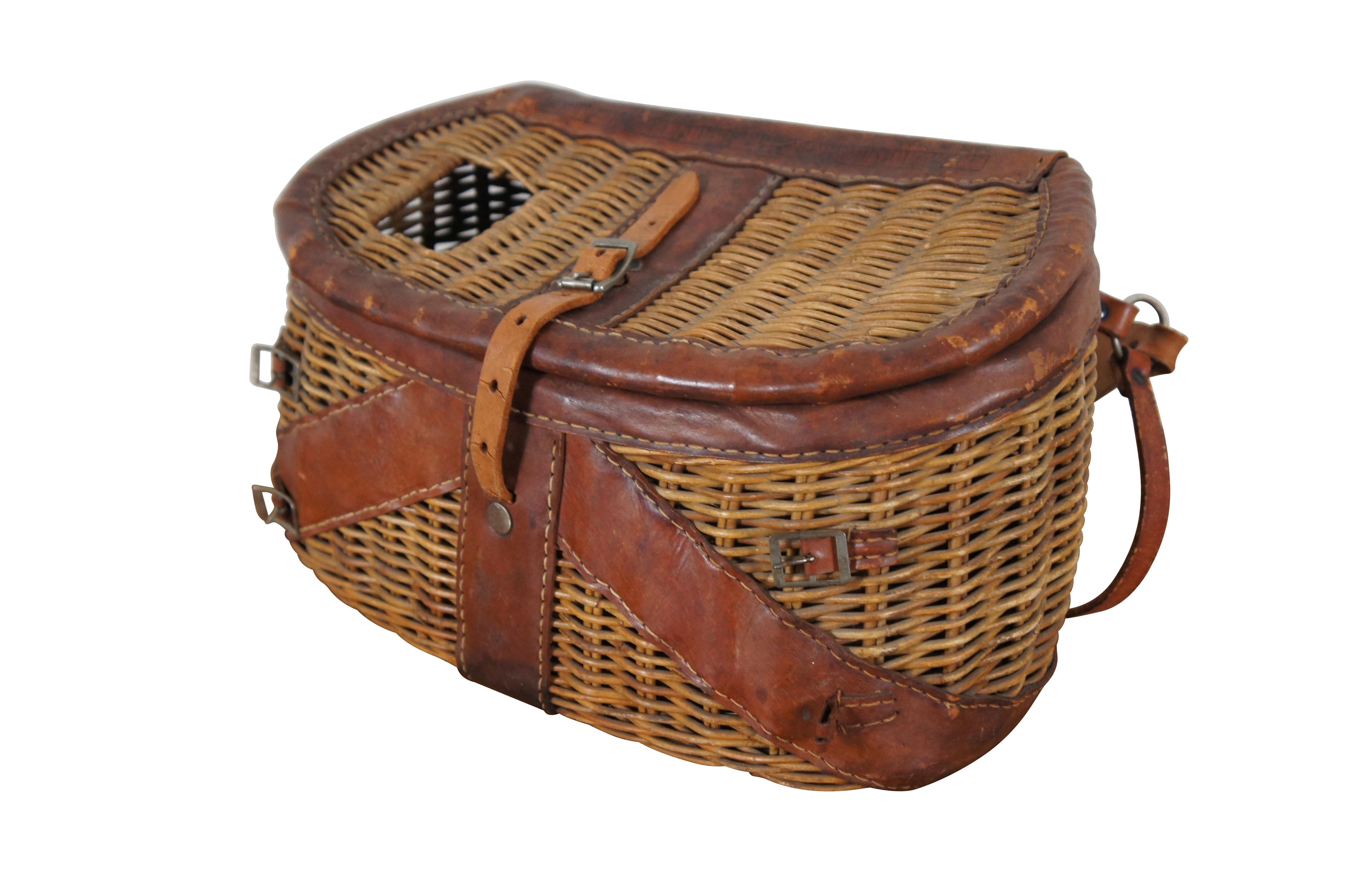 Montana fly fishing vintage creel, circa 1930-1940's. The creel features a tightly woven wicker, leather wrapped rims to the lids, support for the shoulder strap, and a buckle and strap closure.  Made in China

Dimensions:
14.5” x 8” x 8” (Width x