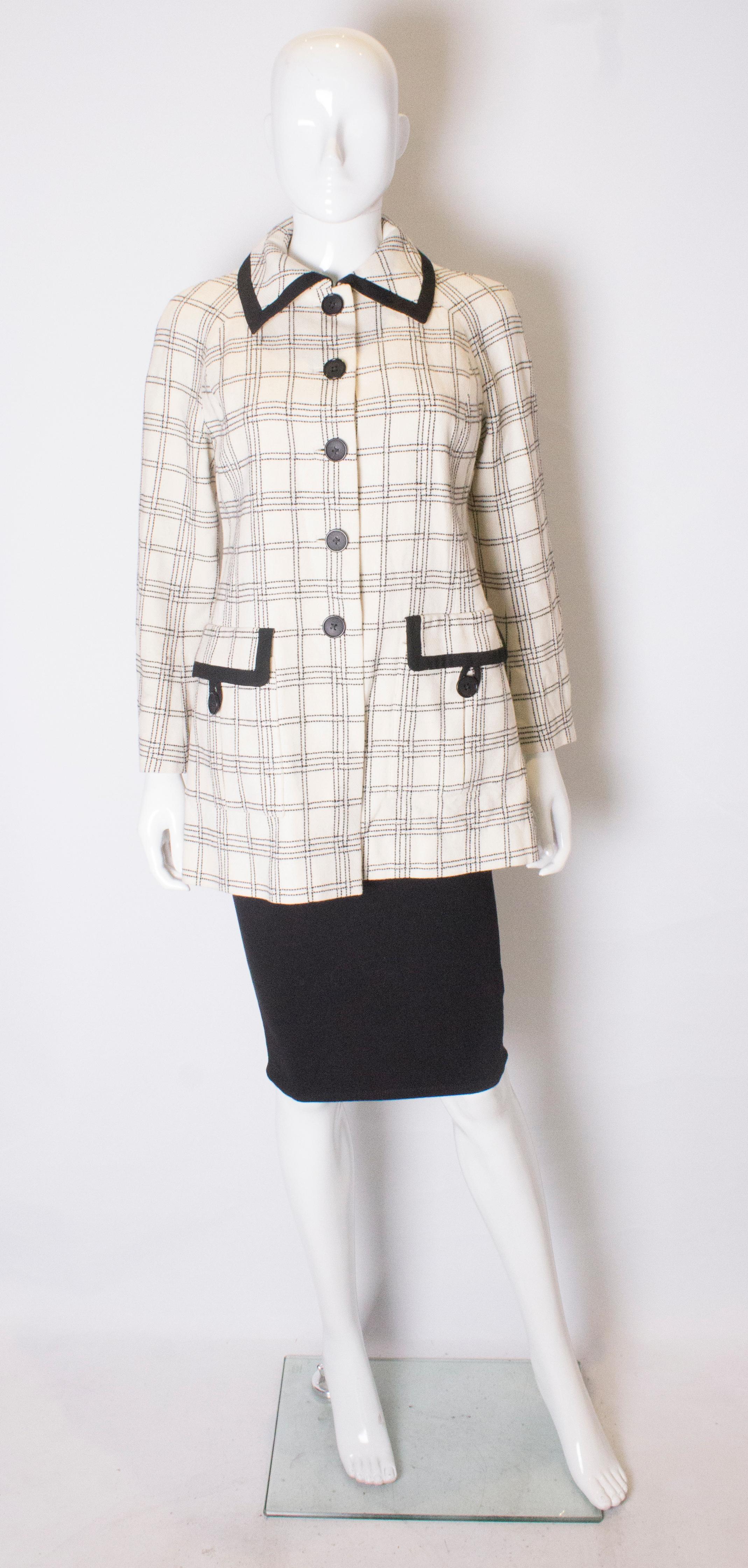 A cute jacket for Spring with great pocket detail. The jacket has an ivory background with black stitching and trim detail. It has two pockets with fold over flaps and button loops. It has a five button opening and is fully lined.