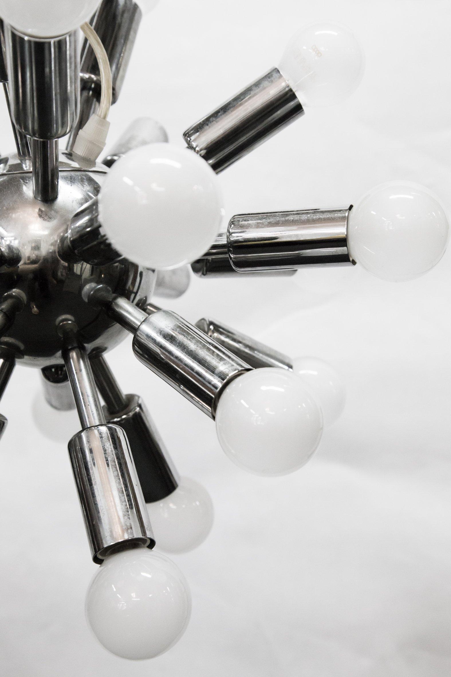 Possibly 1960s Italian design, this chrome-plated chandelier features 24 arms with bulbs, an adjustable steel cord for height and transparent cable. It's in working order and good condition.
