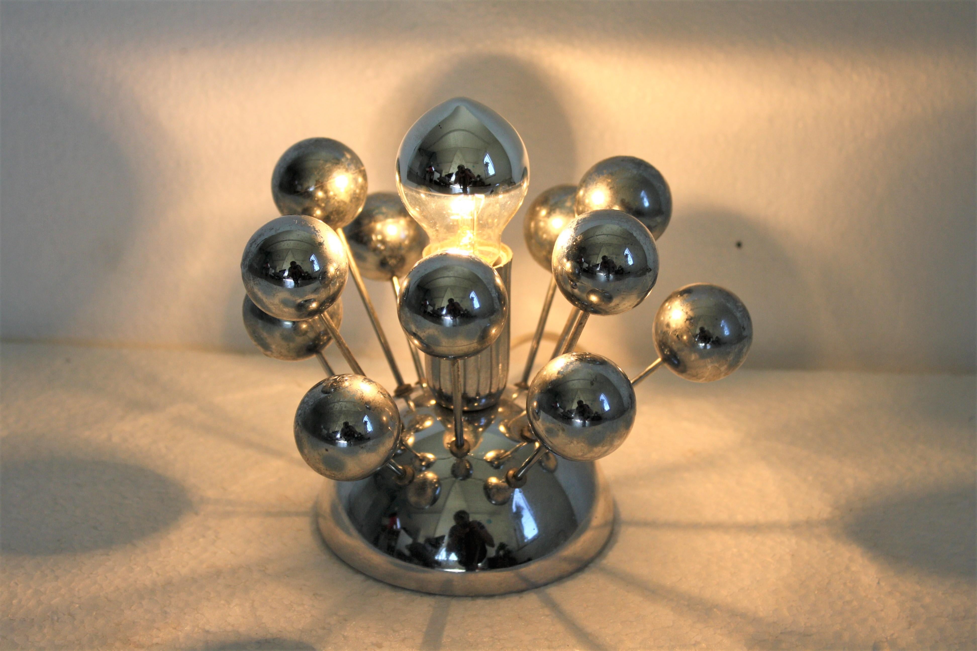 Rare small Sputnik table lamp.

Just like the famous Sputnik chandeliers, this table lamp consists of chromed plastic spheres mounted on chromed steel arms.

It has one center mirrored E14 light bulb.

Ideal to use as a bedside lamp.

It