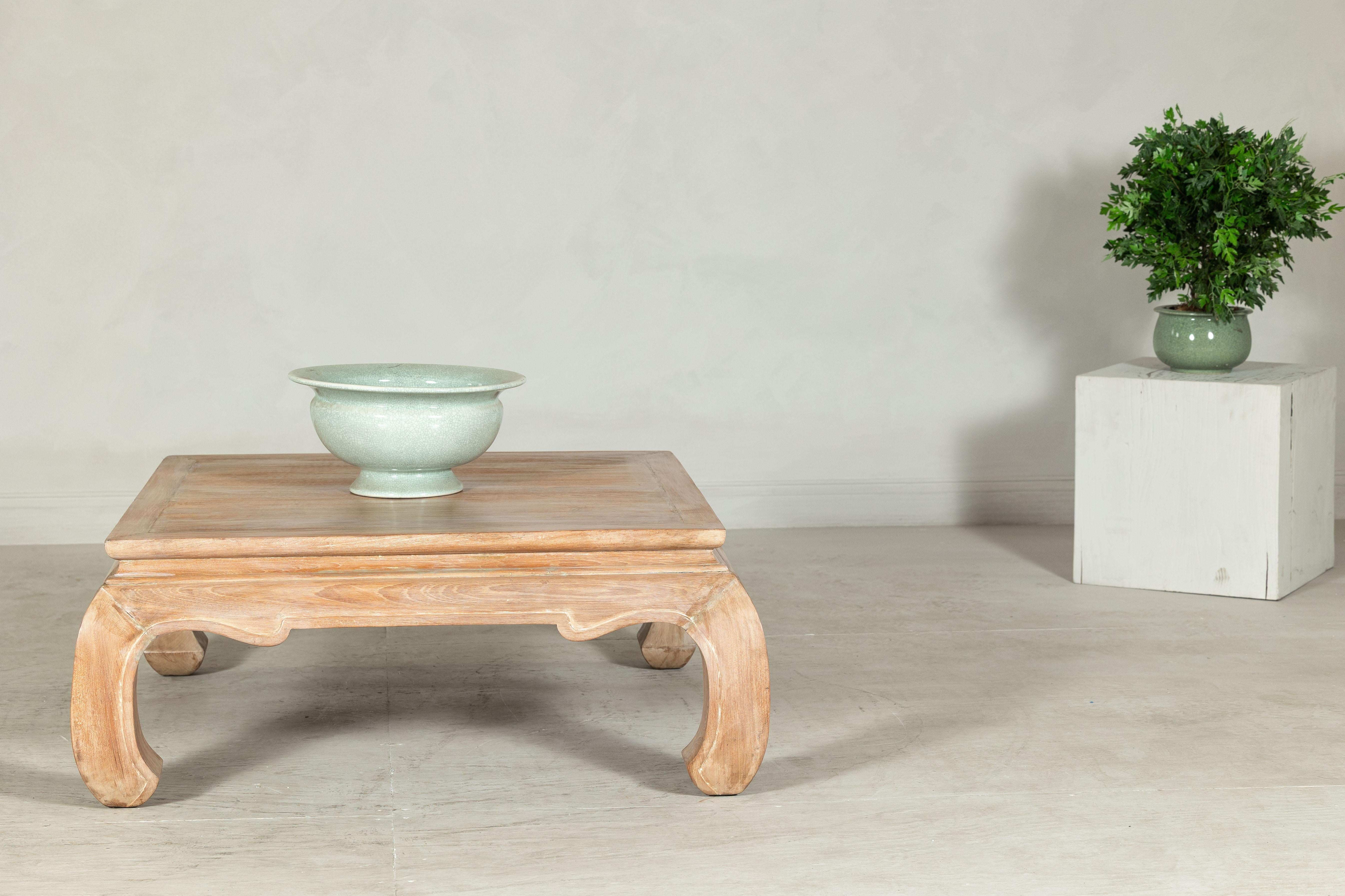 Esta mesa de centro cuadrada vintage muestra la elegancia atemporal del diseño asiático con sus características patas chow y su acabado en madera ligeramente blanqueada. Fabricada en madera maciza, la pieza revela sutiles patrones de veteado en su