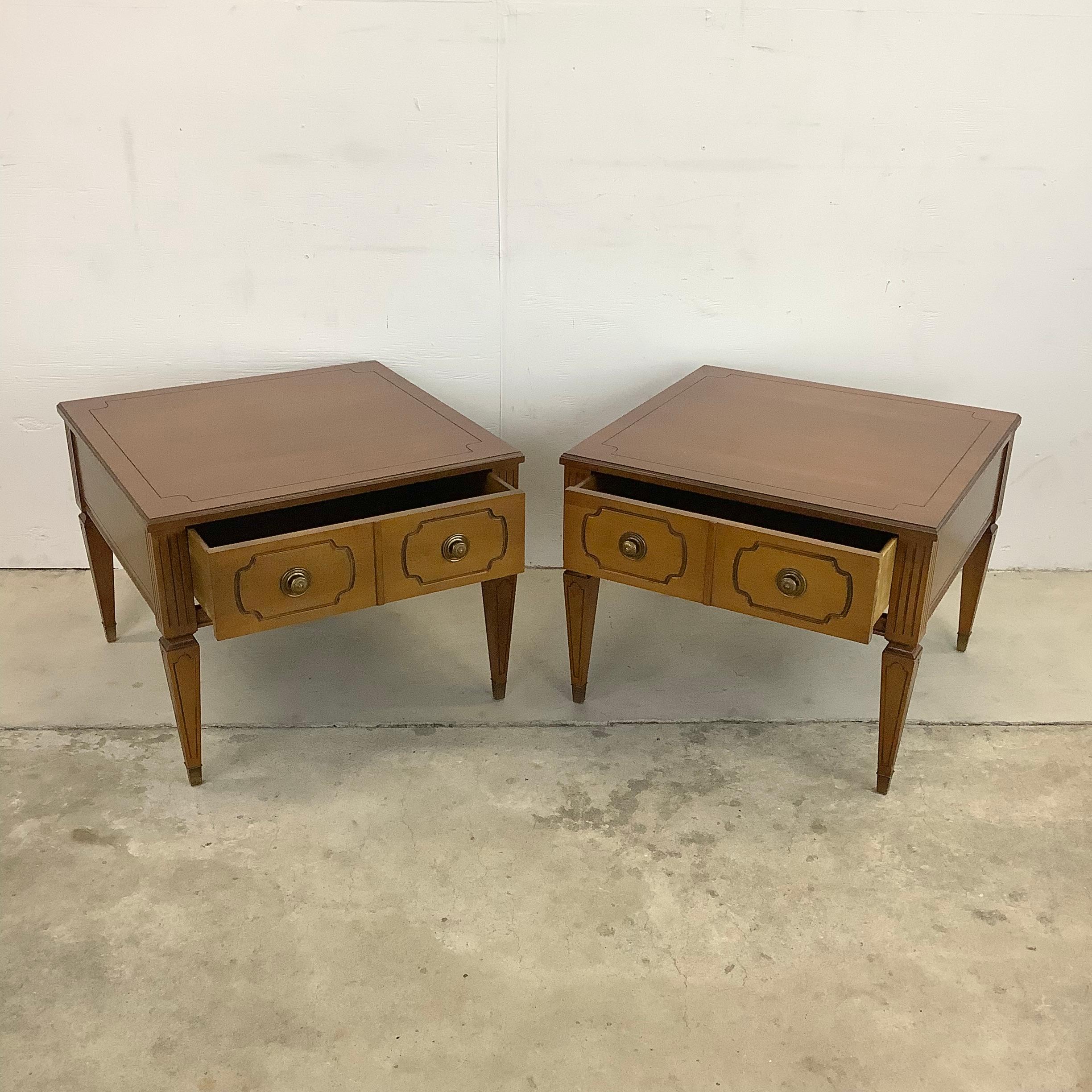 This pair of vintage end tables feature ornate tapered legs, decorative drawer fronts, and spacious single drawer design. The unique style and large square orientation of the pair makes for an excellent addition to any interior as a set of lamp