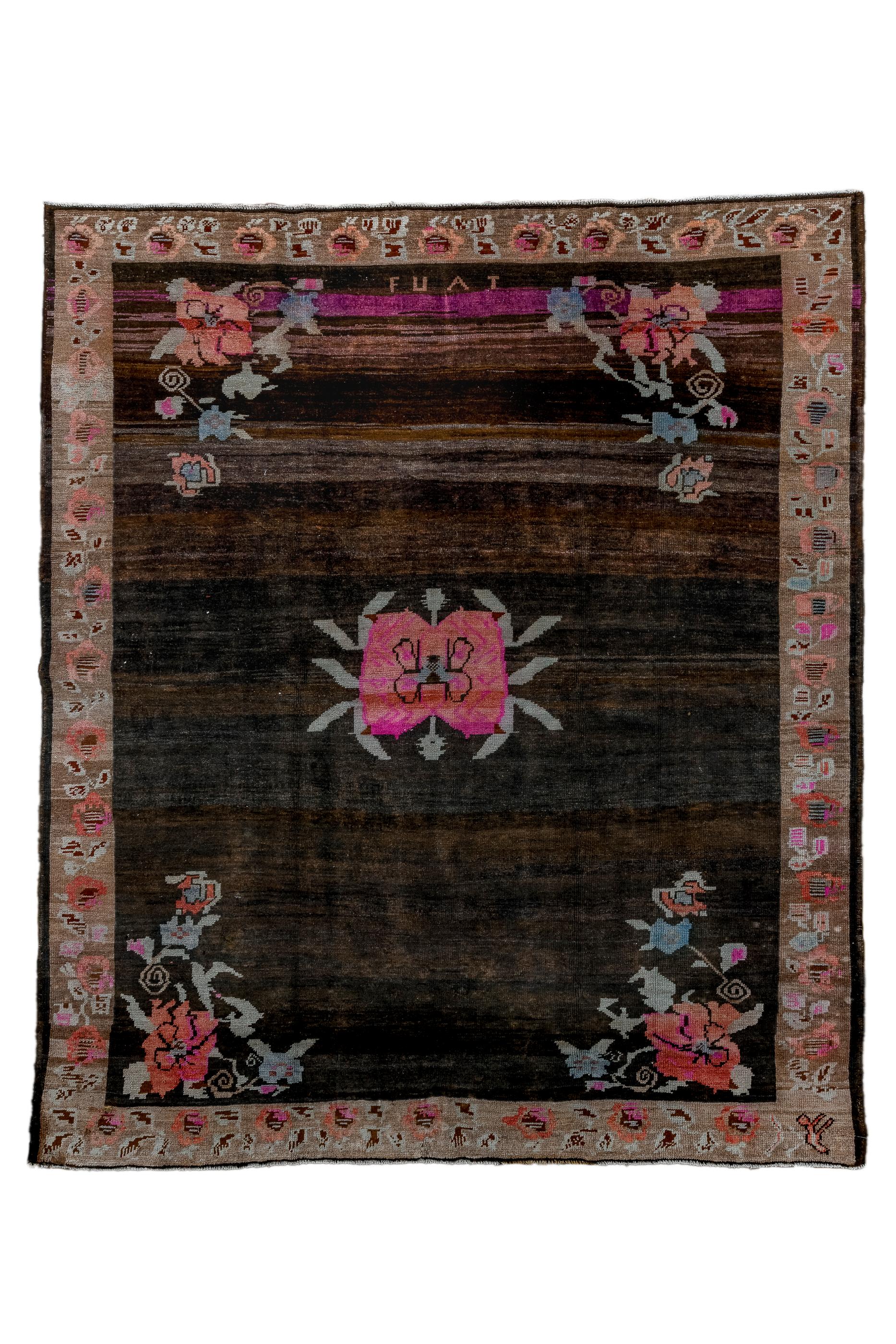 The abrashed, mostly open charcoal field displays a mostly pink, central, pinched medallion with ten leafy extenders and two tiny pendants, along with openwork flower assemblies in all four corners. Signed “Fuat”, presumably the master weaver. Green