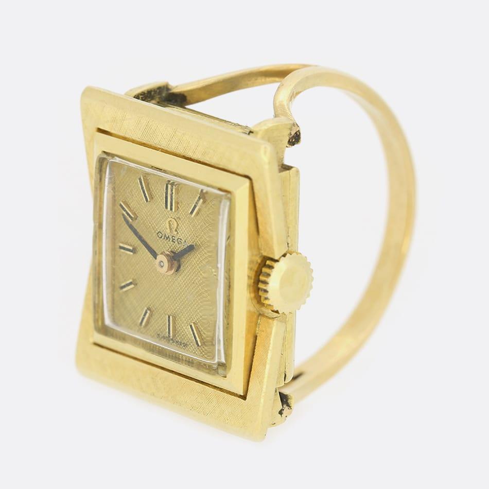 Voici une magnifique bague de montre Omega Vintage. Elle présente un visage carré avec un cadran doré, des index noirs et des aiguilles noires. La montre possède la plupart de ses pièces d'origine, y compris le cadran, le cadran et les aiguilles,