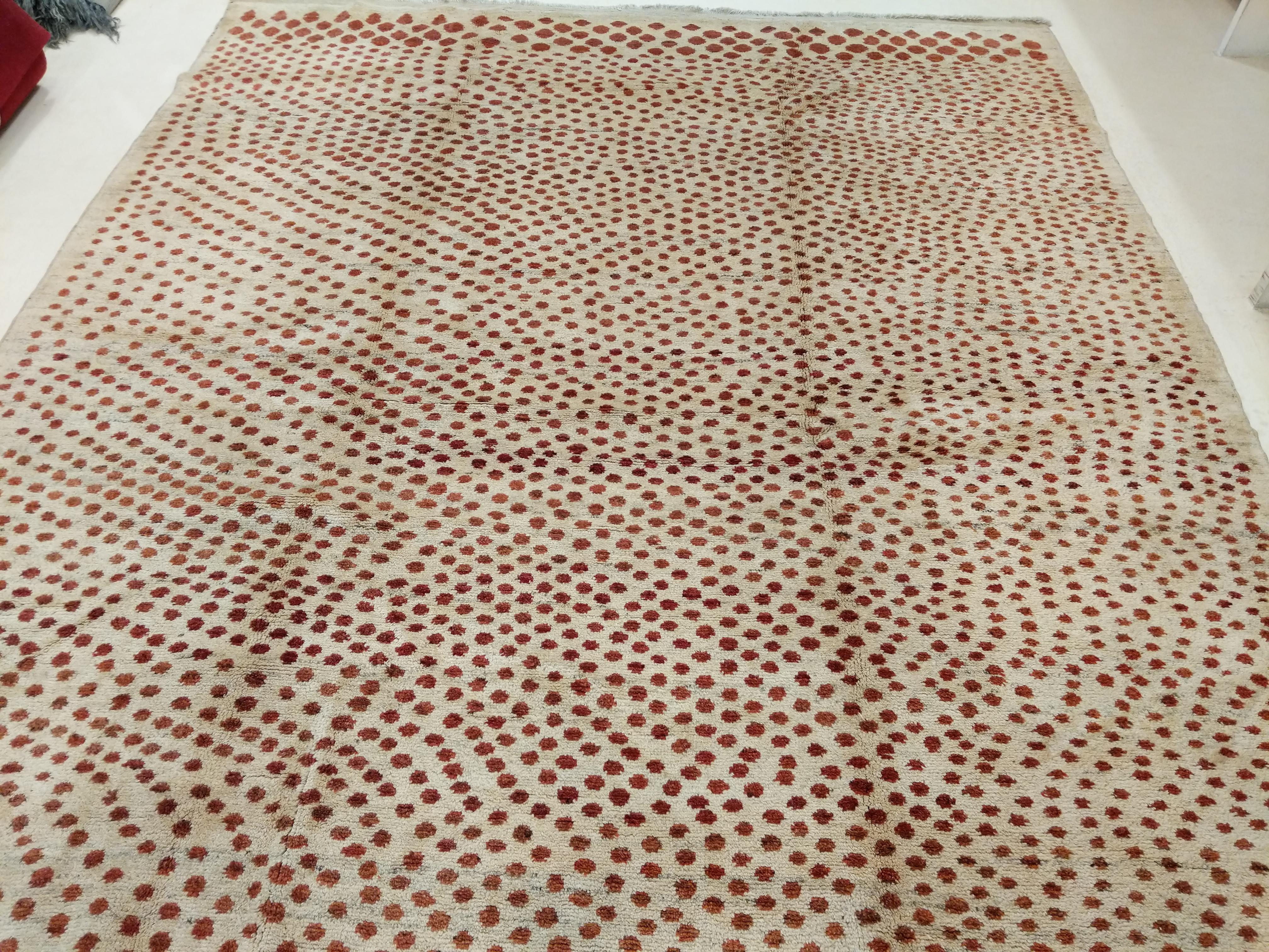 A finely woven wool rug distinguished by a pointillist pattern of red dots of different dimensions punctuating a natural beige background. The resulting pattern mimics the design we see on leopard skins, and has great decorative appeal. Rugs of this