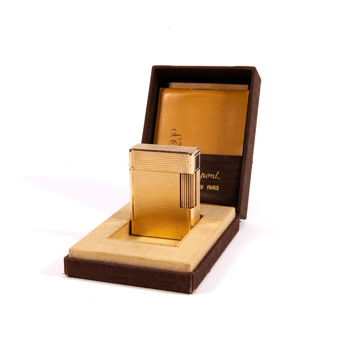 Vintage Gold Plated Small Linge 1 BR ST Dupont Lighter 1980s In Box

The iconic S.T. Dupont name is known for quality, well-made cigarette lighters and other luxury implements. The company’s origin can be traced to Simon Tissot-Dupont opening his
