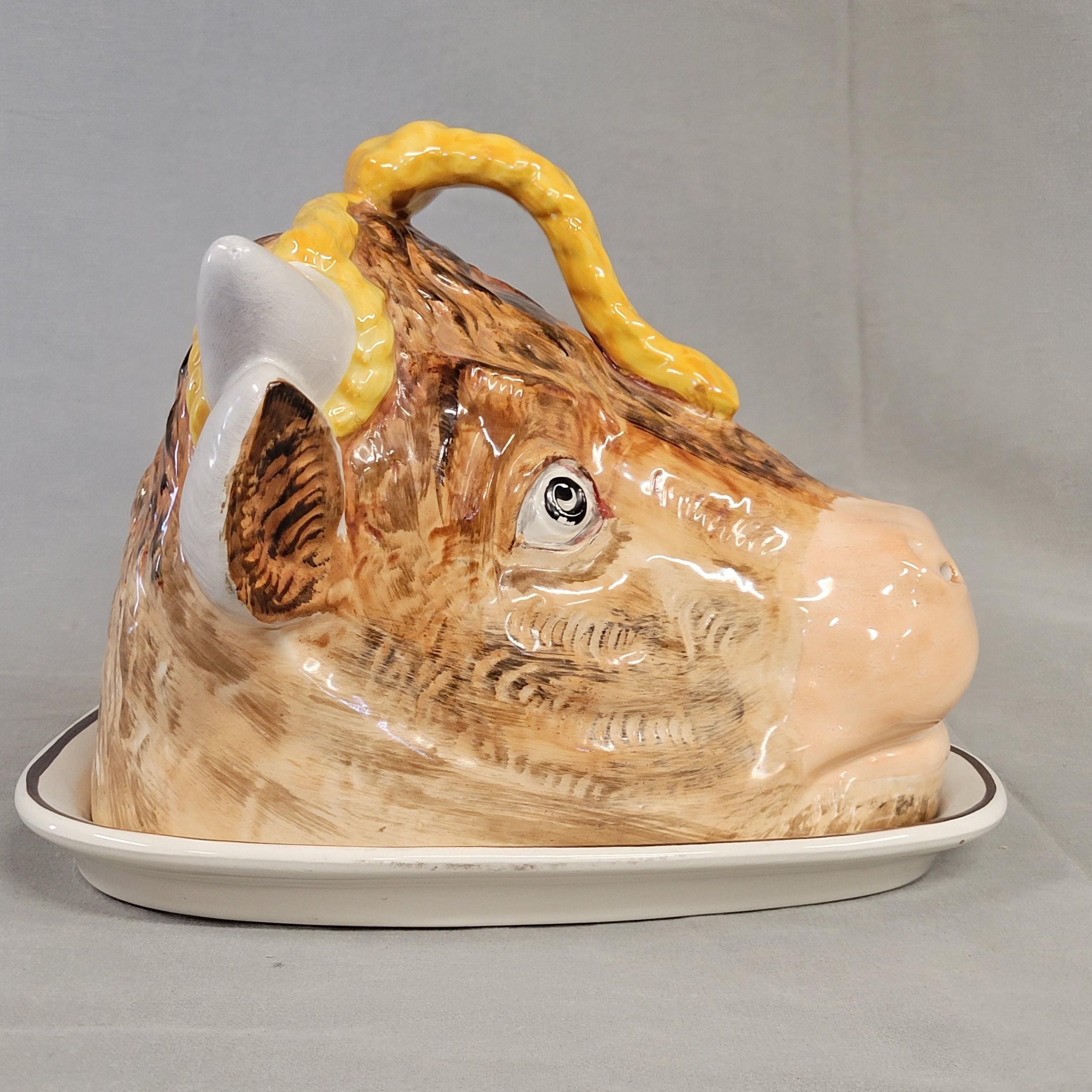 Un affascinante piatto da formaggio inglese in maiolica smaltata di Staffordshire a forma di testa di mucca. Il piatto è triangolare, in grado di ospitare uno spicchio di formaggio, con angoli arrotondati e un labbro rialzato in modo che il