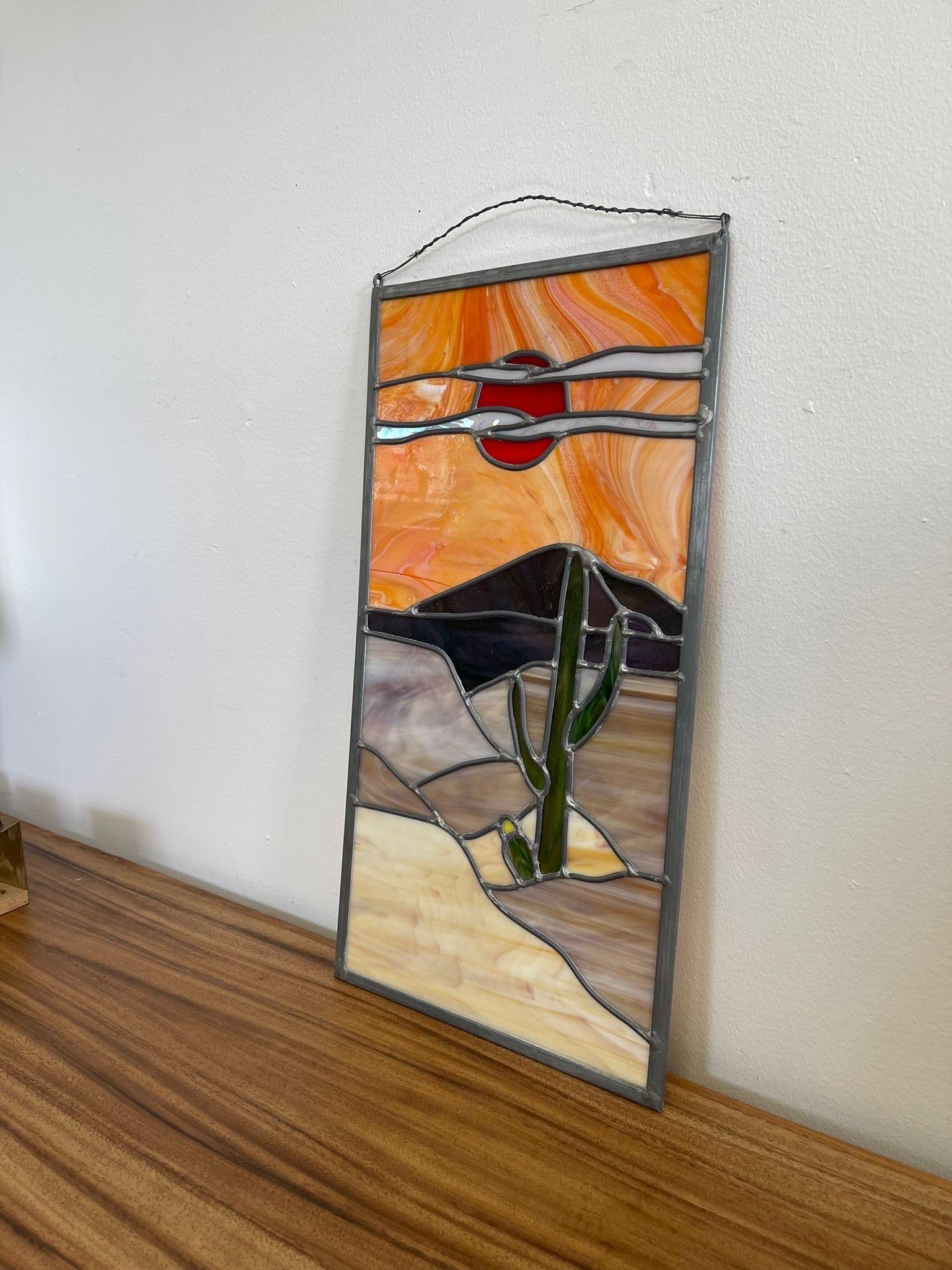 Diese Glasmalerei im Vintage-Stil besticht durch ihre leuchtenden Farben und ihre Retro-Atmosphäre. Der orangefarbene Himmel und der Sand haben einen marmorierten Effekt. Silberfarbene Metalldetails und Einrahmungen. Vintage Condition Konsistent mit
