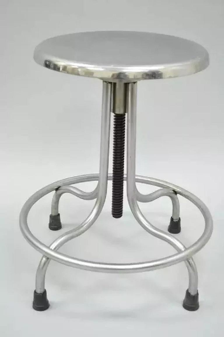 Vintage Stainless Steel American Industrial Modern Steampunk Adjustable Stool. Well-constructed American made medical or dental stool features a polished solid steel metal frame, swag legs, rubber capped feet, footrest, original label and adjustable