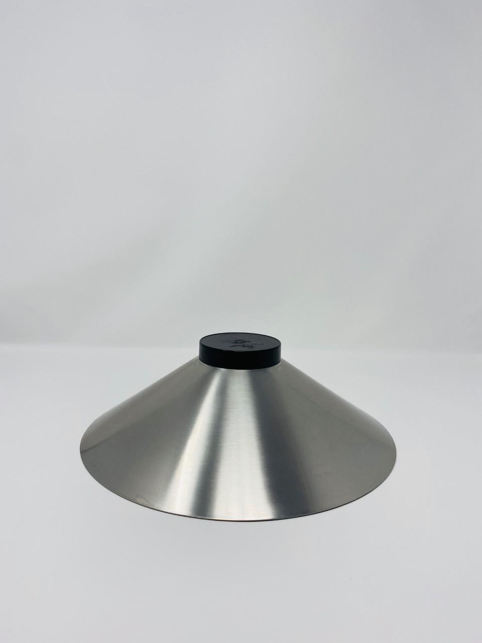 This vintage stainless steel bowl is simple yet graphic and a statement piece of design. The timeless simple, yet bold lines in brushed stainless steel envelop into a cone shape that rest on a black plastic base. Beautiful piece that will enhance