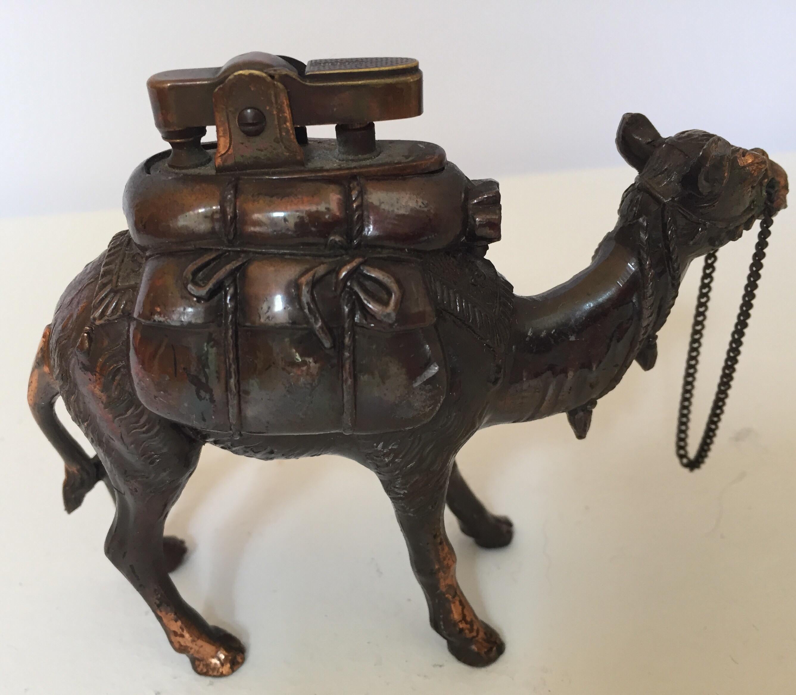 Vintage figure of a standing camel metal table lighter,
Cast metal brass camel figure in walking position with its head facing forwards carrying packs. 
Copper bronzed color like patina finish.
 