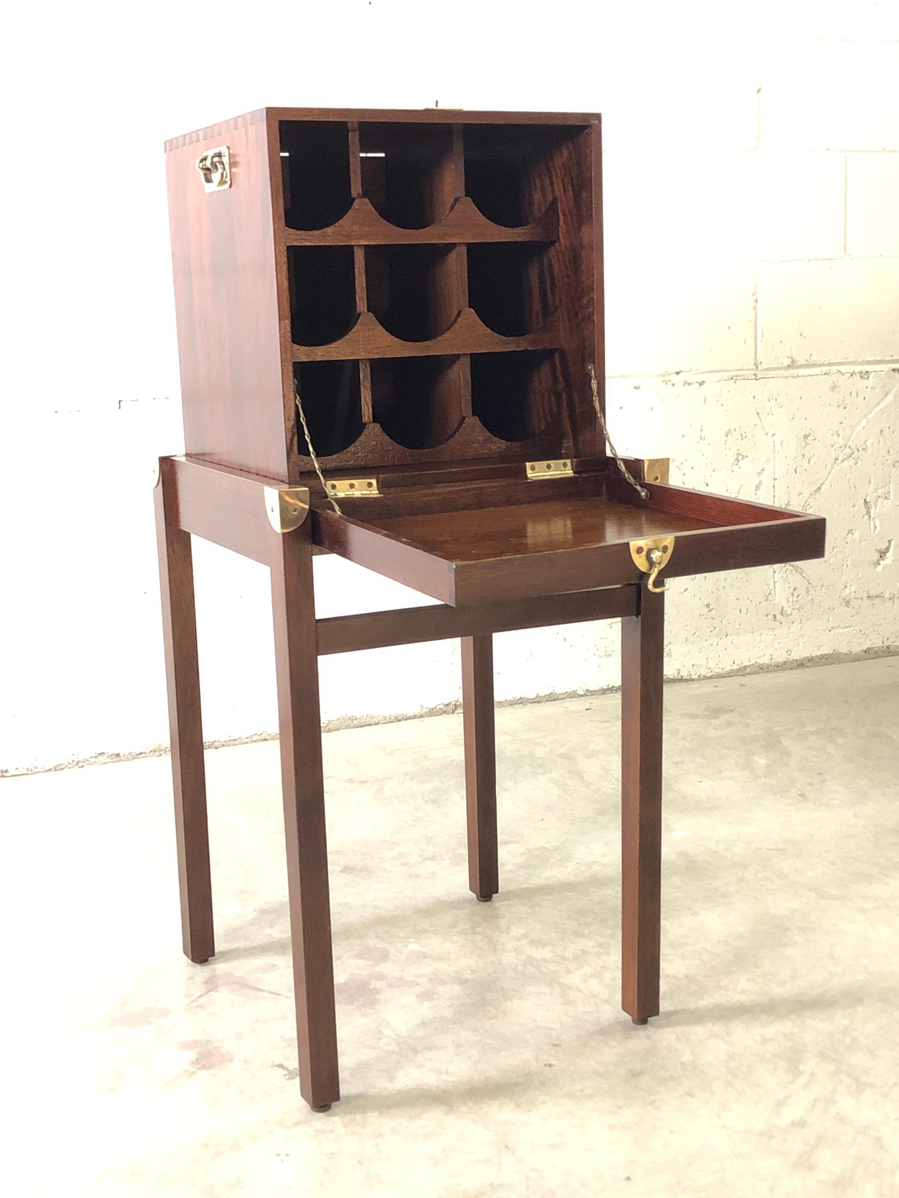 Vintage mahogany wood wine rack on a stand. The rack has a dovetailed box with brass accents and sits on a stand. The rack holds nine wine bottles and the front comes down to create a shelf. Excellent condition. No marks.