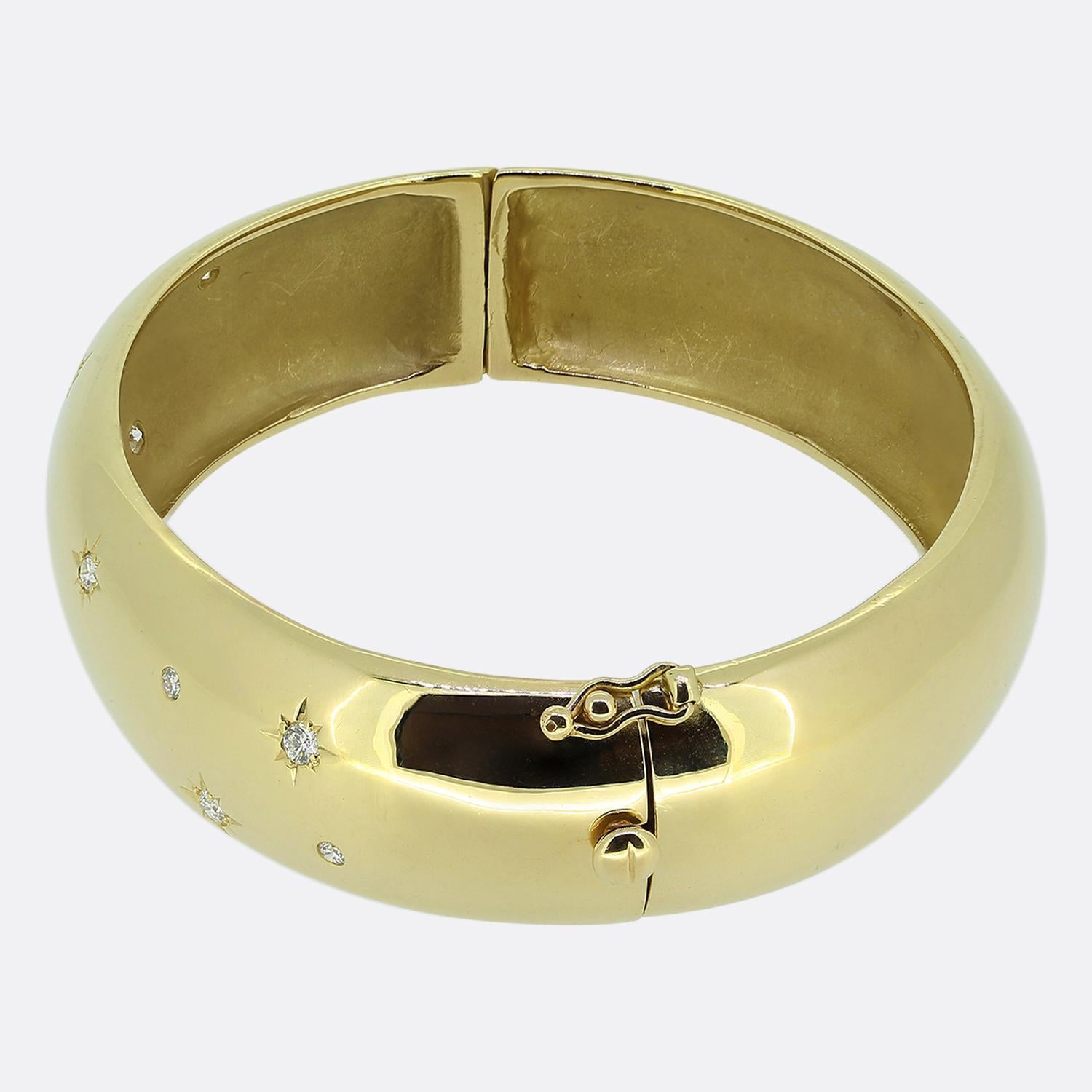 Here we have a captivating bangle crafted from 14ct yellow gold. This bold vintage piece features a smooth, polished surface adorned with a series of bright white round brilliant cut diamonds; the larger of which have all been star-burst set. The
