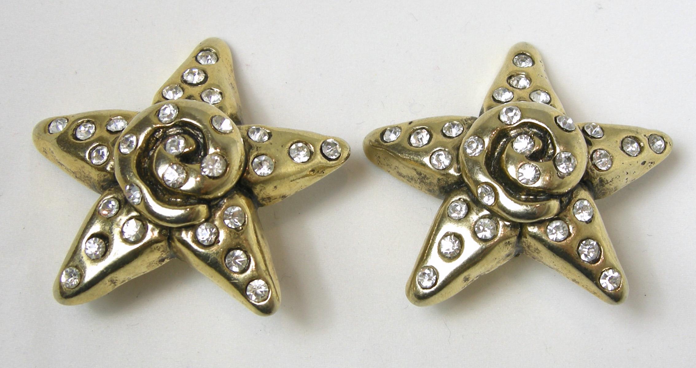 These vintage earrings have a star design with clear crystal accents in a gold tone resin finish.  In excellent condition, these clip earrings measure 2” across.