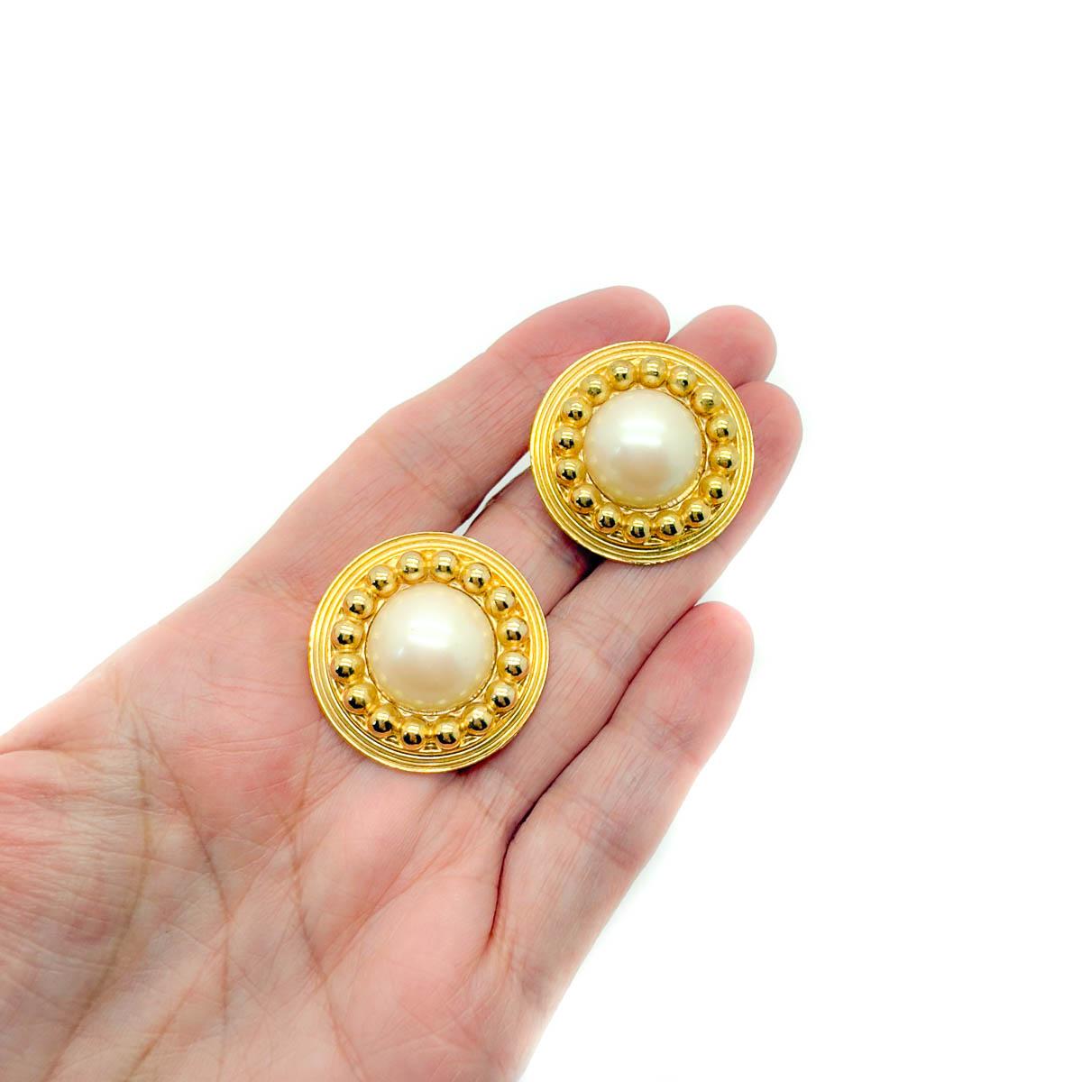 Diese glamourösen Vintage-Ohrringe mit Perlenbommel strahlen zeitlose Eleganz aus. Mit ihren schimmernden Perlen, die in reichhaltig vergoldetes Metall gefasst sind, fangen sie die Eleganz vergangener Epochen ein und sind gleichzeitig unbestreitbar