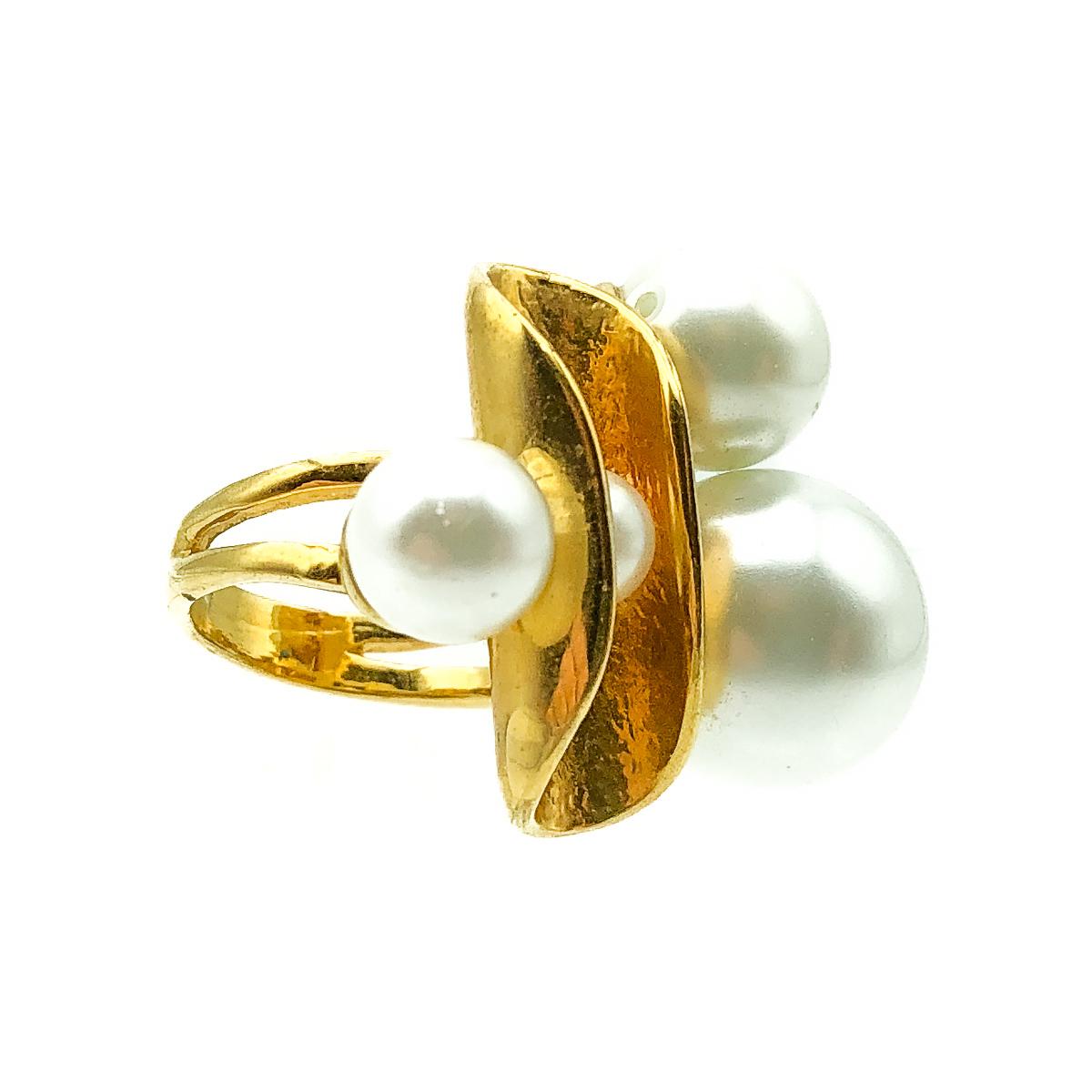An exquisite Vintage Statement Pearl Ring dating to 1980s. Crafted in glass simulated pearl and gold plated metal. Featuring three lustrous simulated pearls of varying size settled around a fold of gold hued metal. The fourth pearl is clasped within