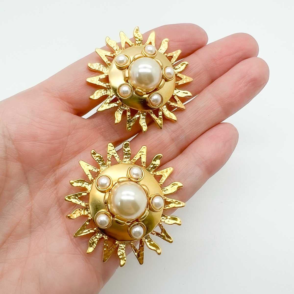 Un impresionante par de pendientes Vintage Pearl Sunburst. Un gran rayo de sol dorado y lustroso adornado con perlas intemporales. Una fascinante declaración de estilo.

Una belleza sin firmar. Un raro tesoro. Que una joya no lleve el nombre de un