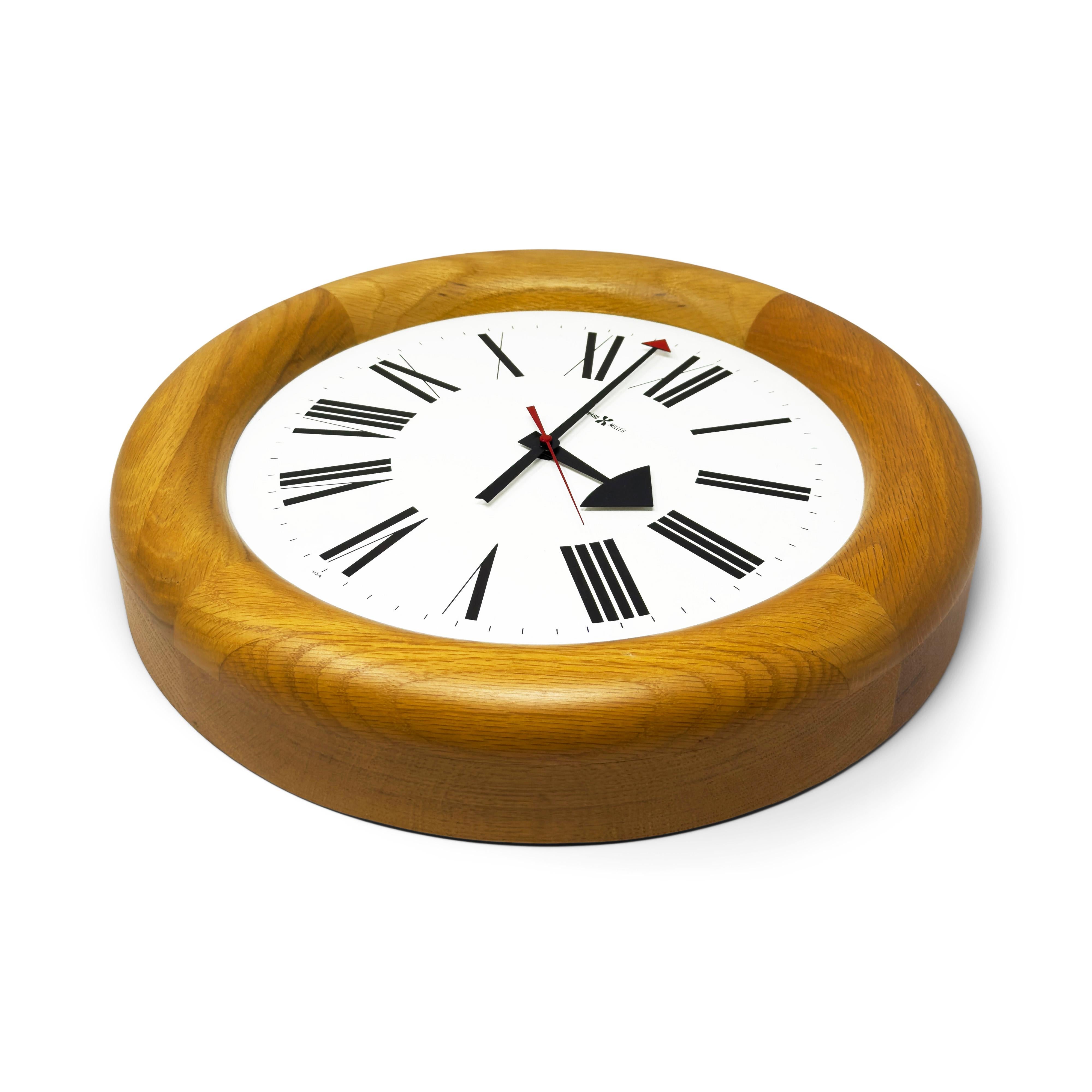 Une horloge murale moderne du milieu du siècle, parfaitement conçue par Arthur Umanoff pour le grand fabricant d'horloges Howard Miller.  Le modèle 611 Stationmaster possède un boîtier rond en chêne massif, un cadran blanc avec des chiffres romains