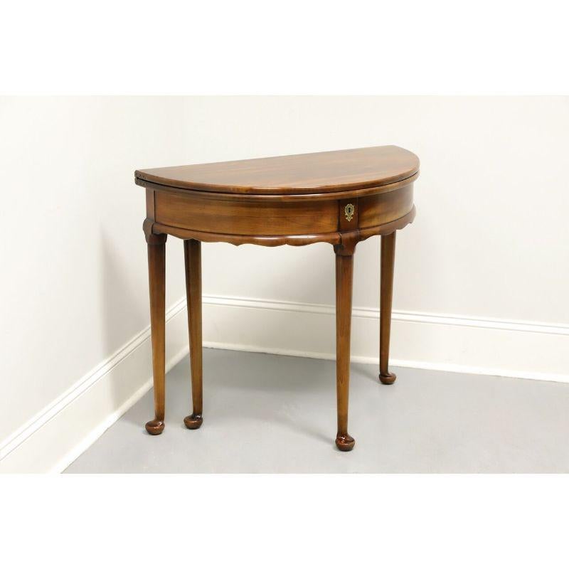 A Georgian style flip top demilune table by Statton Furniture of Hagerstown, Maryland, USA. Solid cherry in Oxford finish with a faux brass lock escutcheon, bow front, carved apron and pad feet. Back gateleg swings out to support top that flips open
