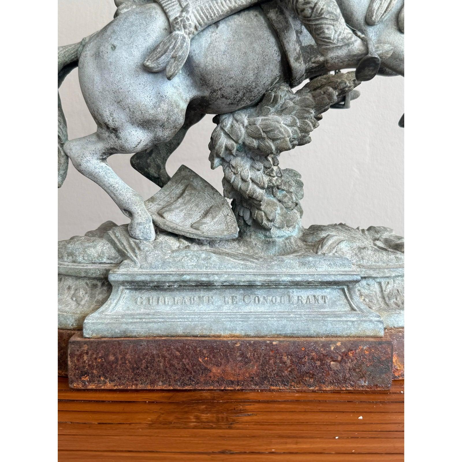 Questa scultura drammatica raffigura una figura trionfante a cavallo della carica, resa con una finitura grigia che richiama il bronzo invecchiato. Con una mano alzata in segno di vittoria e l'altra che comanda le redini, il brano cattura un momento