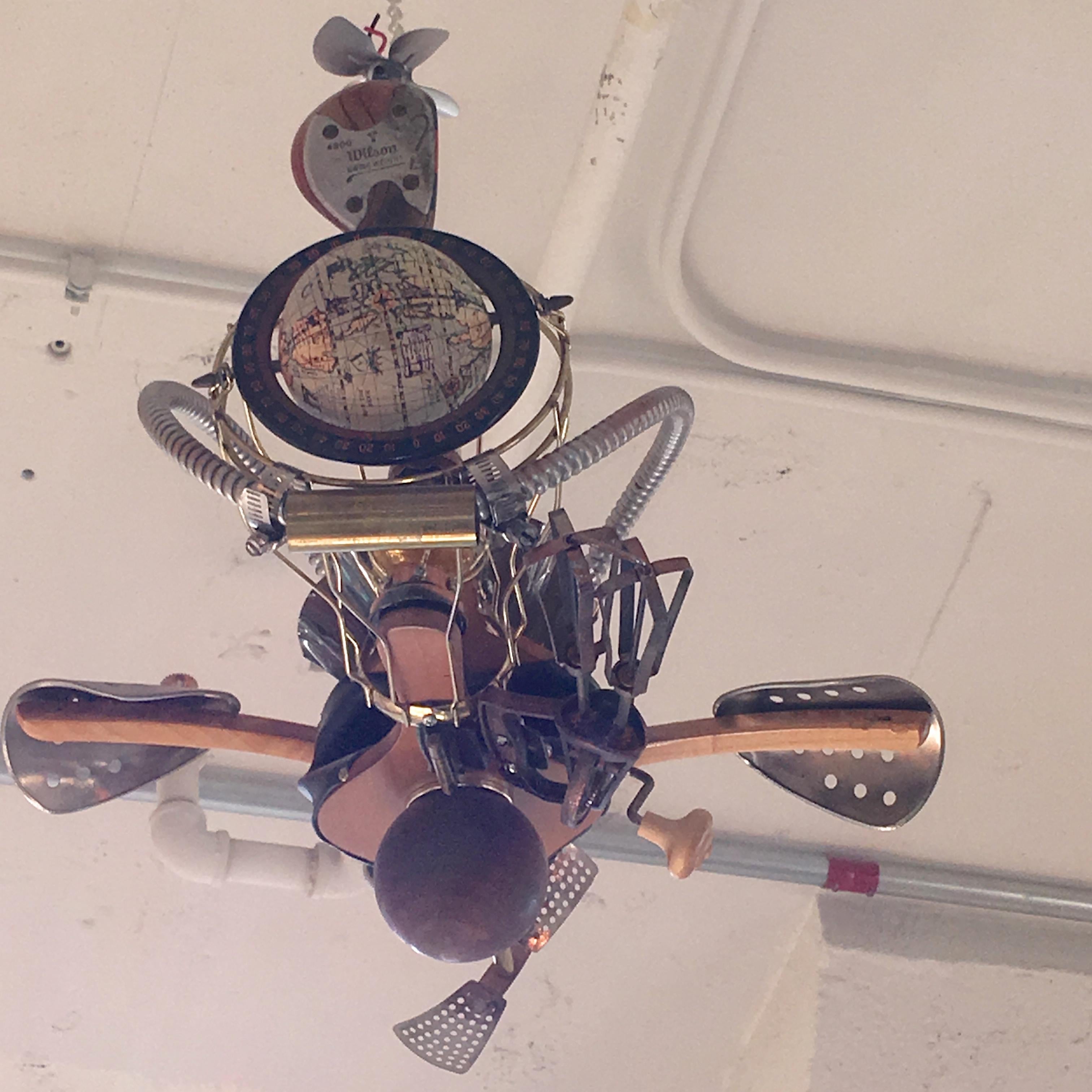 Humorous Steampunk Kinetic sculpture of a fantasy flying machine in the spirit of Chitty Chitty Bang Bang and Wild Wild West, creatively and artistically assembled from found items including: old fashioned manual egg beater, fireplace bellows,
