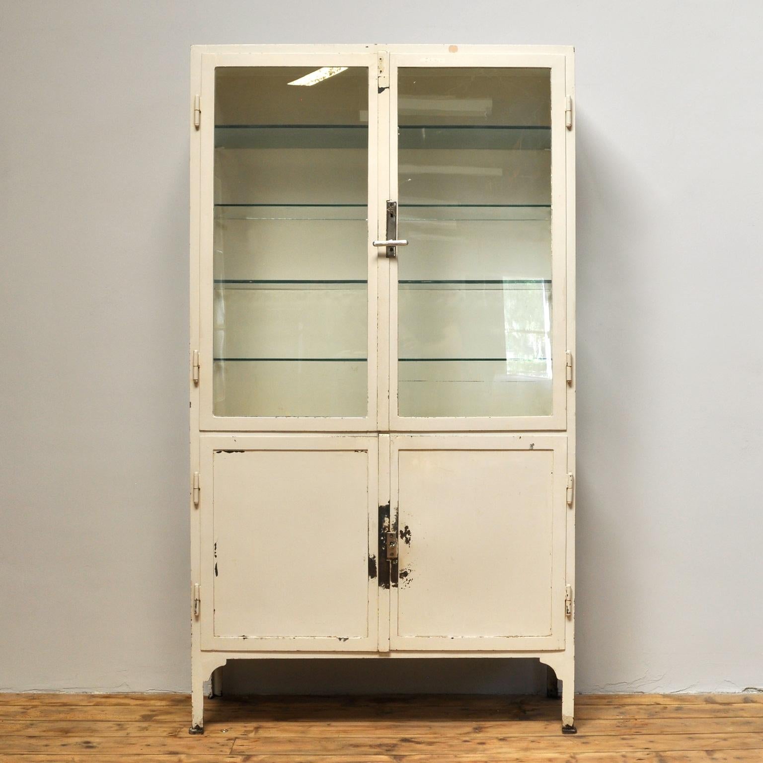 Medical cabinet, produced in de 1940s in Hungary. The cabinet is made of thick iron and antique glass. In the upper part the four glass shelves. In the lower part one iron shelf. The cabinet has a very nice patina, some chips of paint missing. The