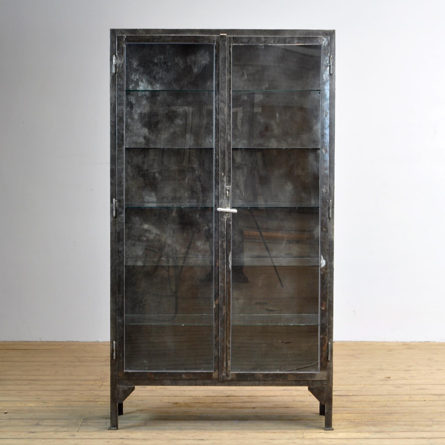 This medical cabinet was produced in the 1940s in Hungary. The cabinet is made from thick iron and glass. With the original lock and handle. The cabinet has been stripped from its paint, polished and treated for rust. It features five glass shelves.
