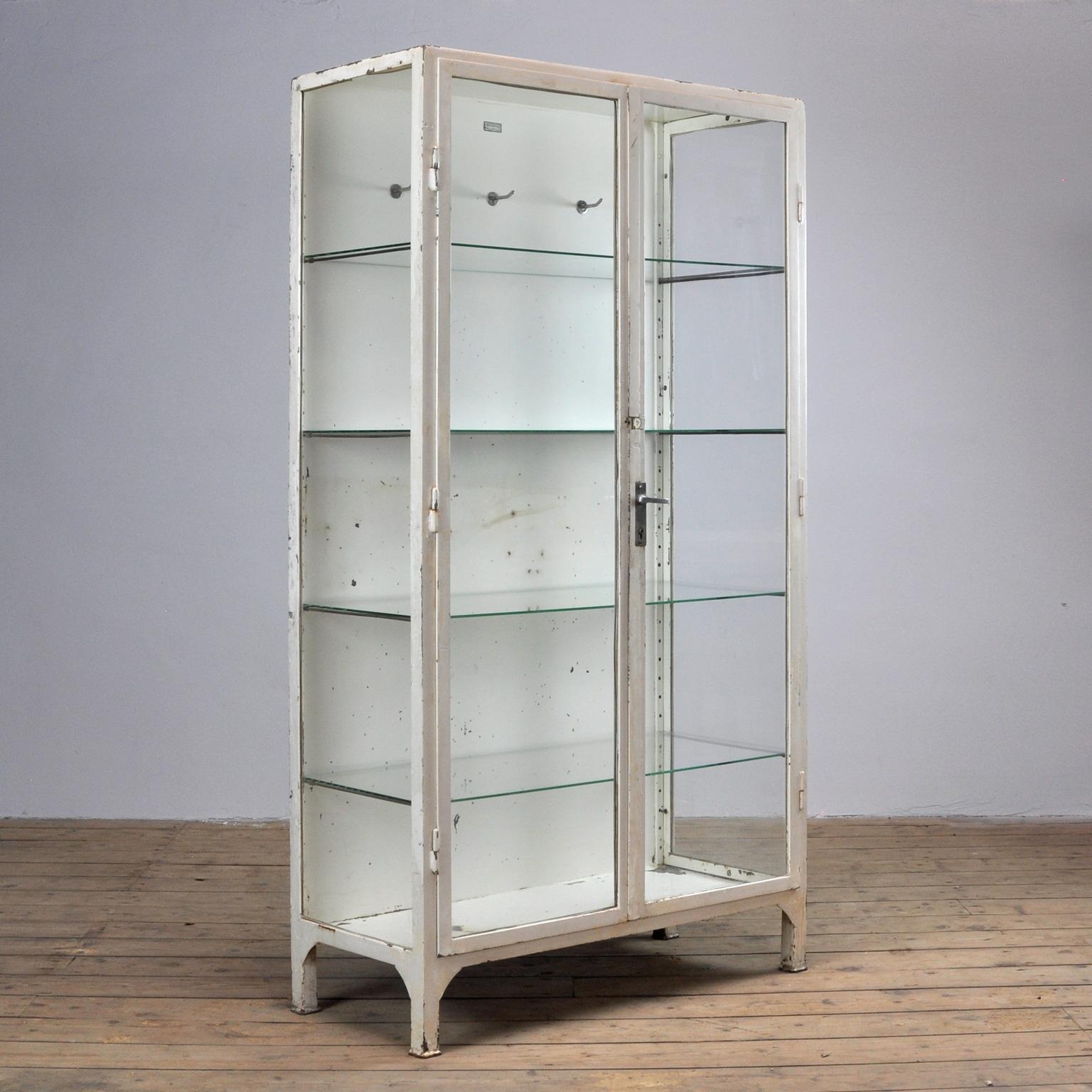This medical cabinet was produced in 1966 in Poland. The cabinet is made from thick iron and glass. It features four new glass shelves and three clothing hooks.