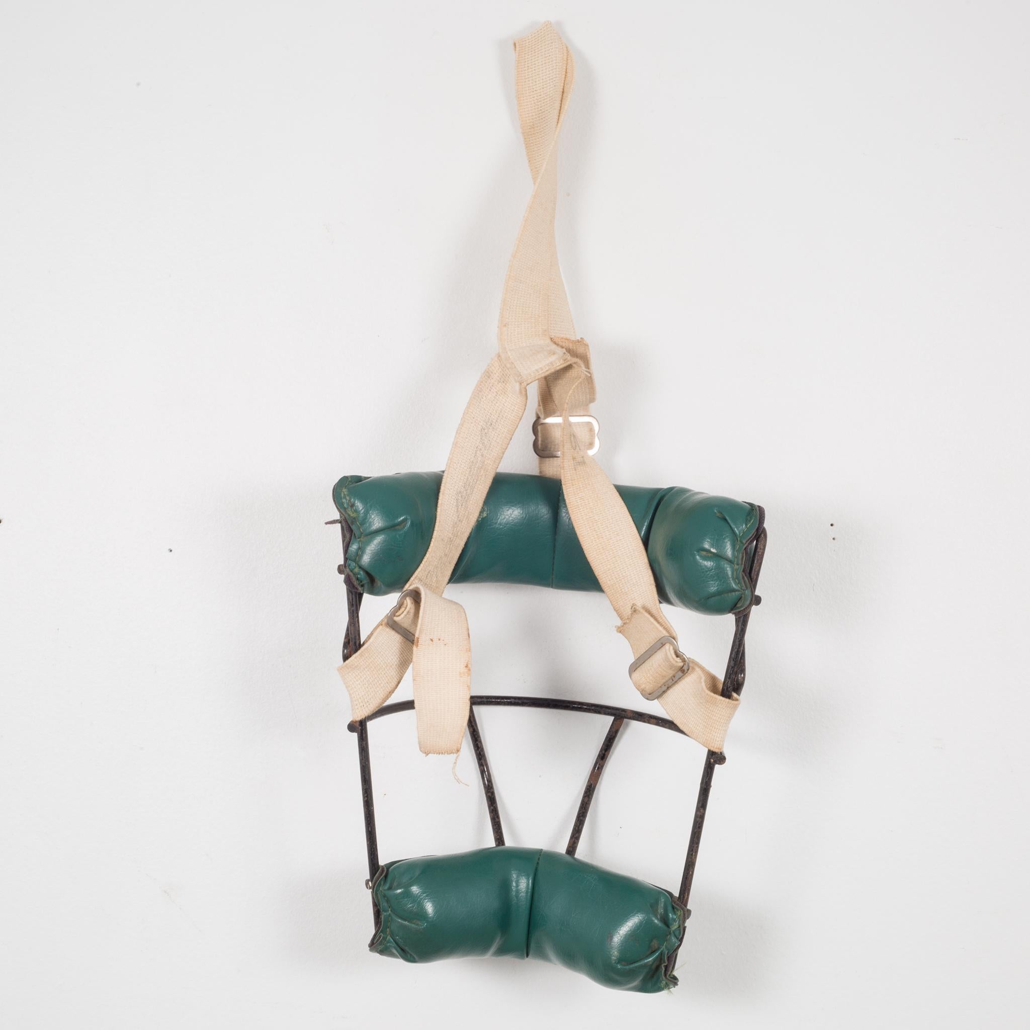 About:

This is an original vintage catcher's mask. The main body is steel with thick, green leather padding and fabric head strap. The padding is held onto the body of the mask by brown leather straps. The piece has retained most of it's original