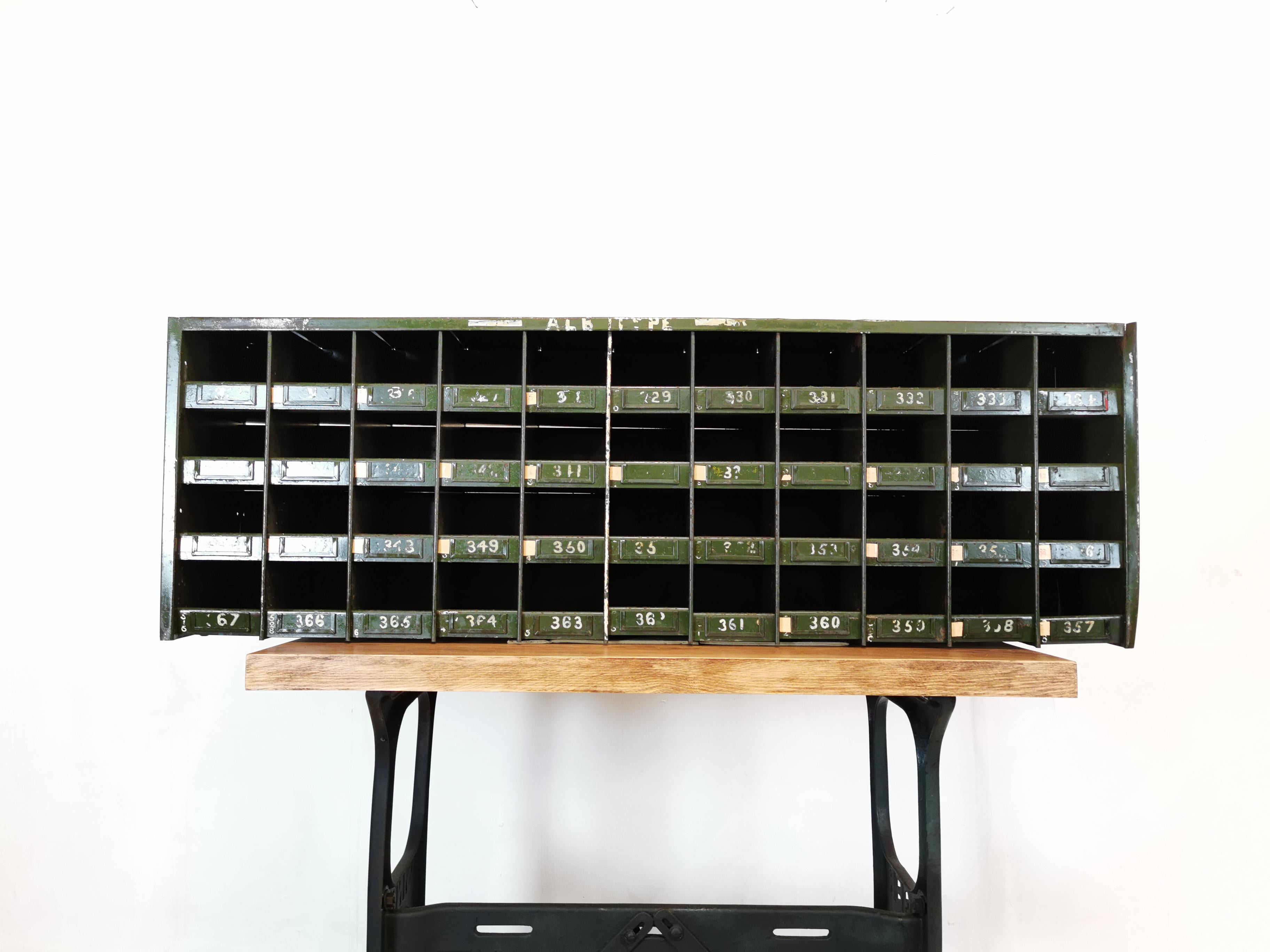 A midcentury industrial steel pigeon hole unit.

A large bank of forty-four open pigeon holes.

Painted with roughly done lettering. Heavy-duty steel.

Table not included.
