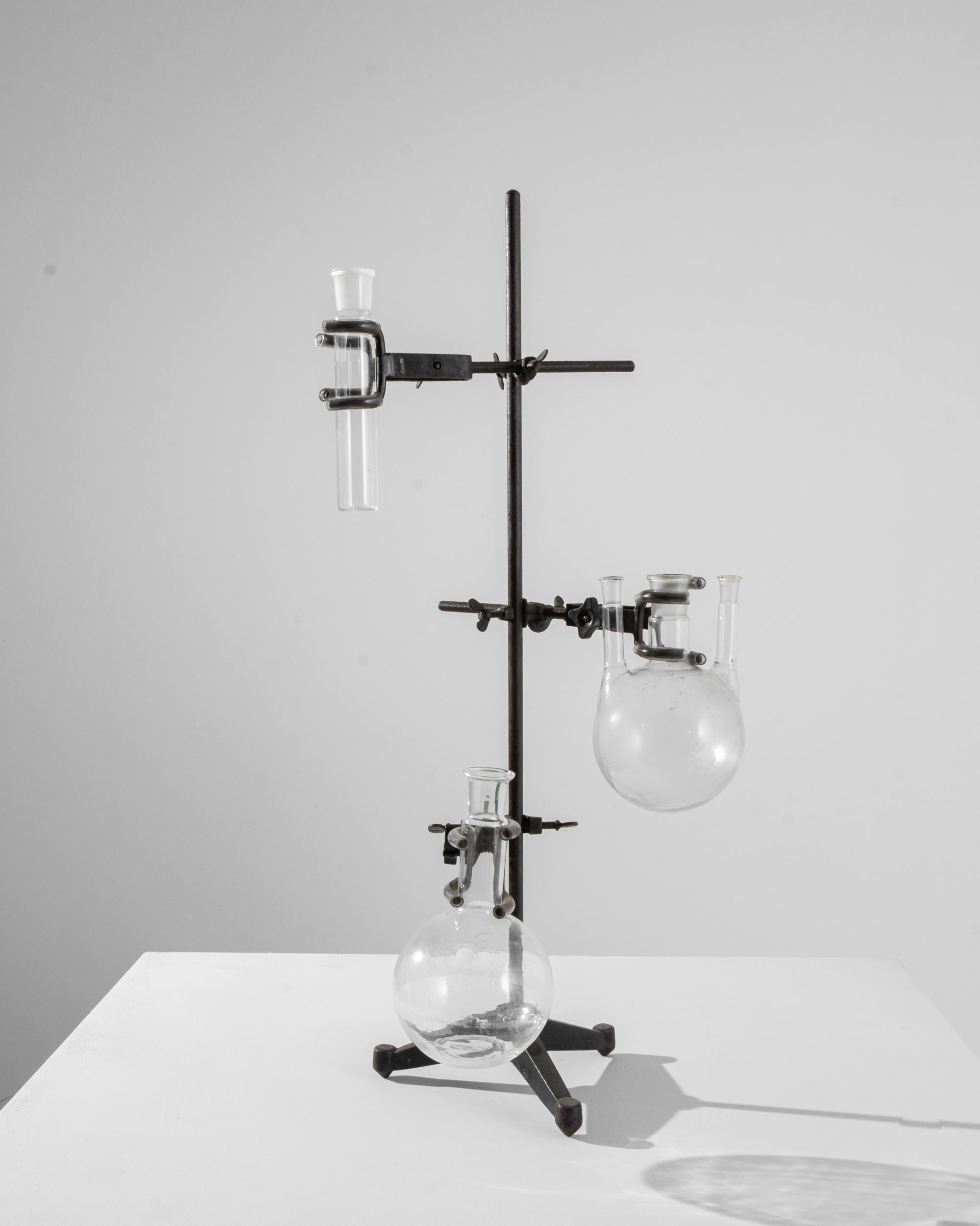 An intriguing and unique accent, this vintage lab-ware stand holds three round-bottomed flasks. Once used as a tool for conducting laboratory analysis or experimentation, the globe-like spheres glint with the crystal clarity of borosilicate. The