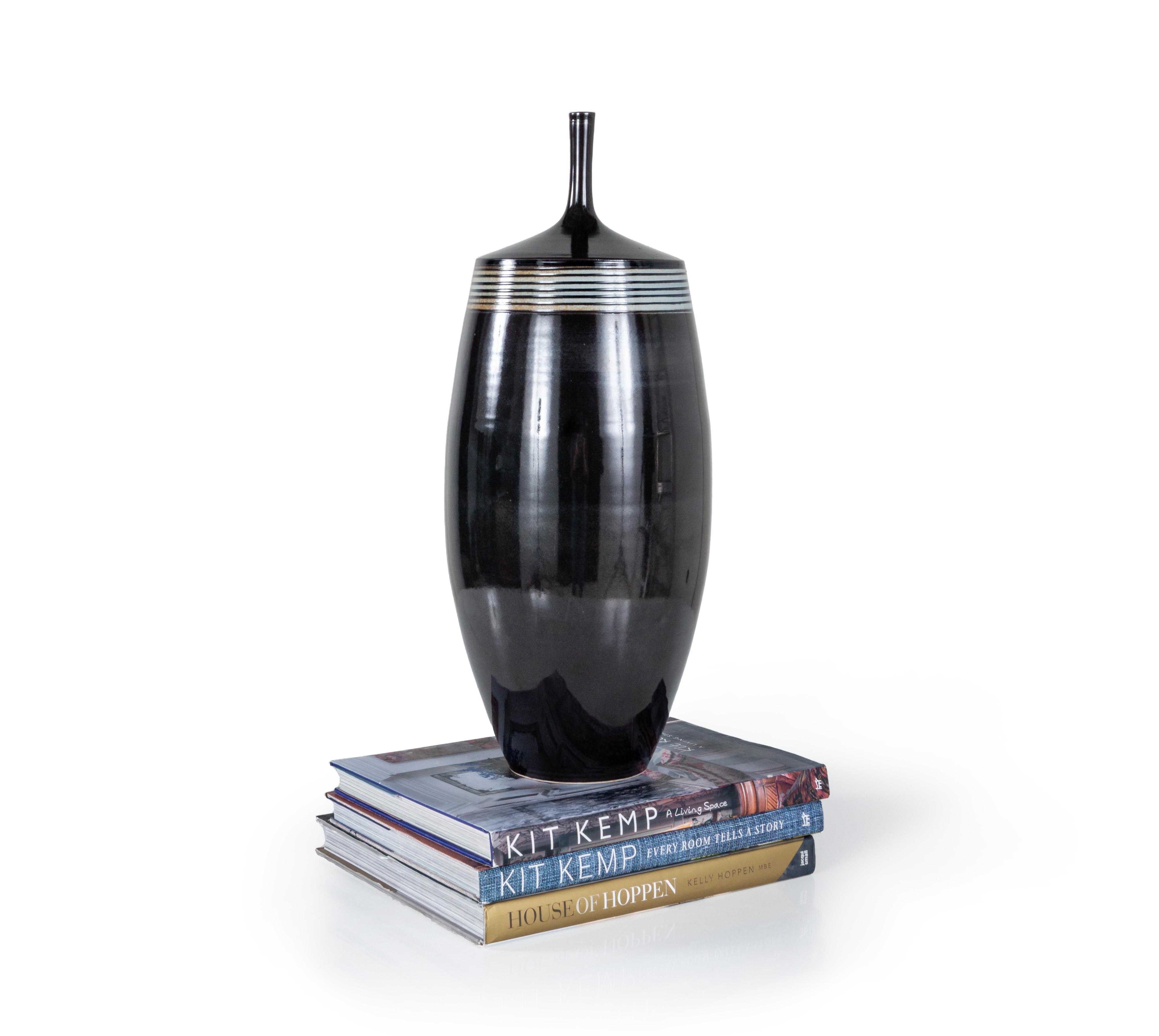 The Vintage Stephen Merritt Vase is a beautiful jar and pottery piece from the acclaimed contemporary artist, Stephen Merritt. The vessel is made of high-fired earthenware and has a glazed polish finish with a subtle striped pattern at the top. This