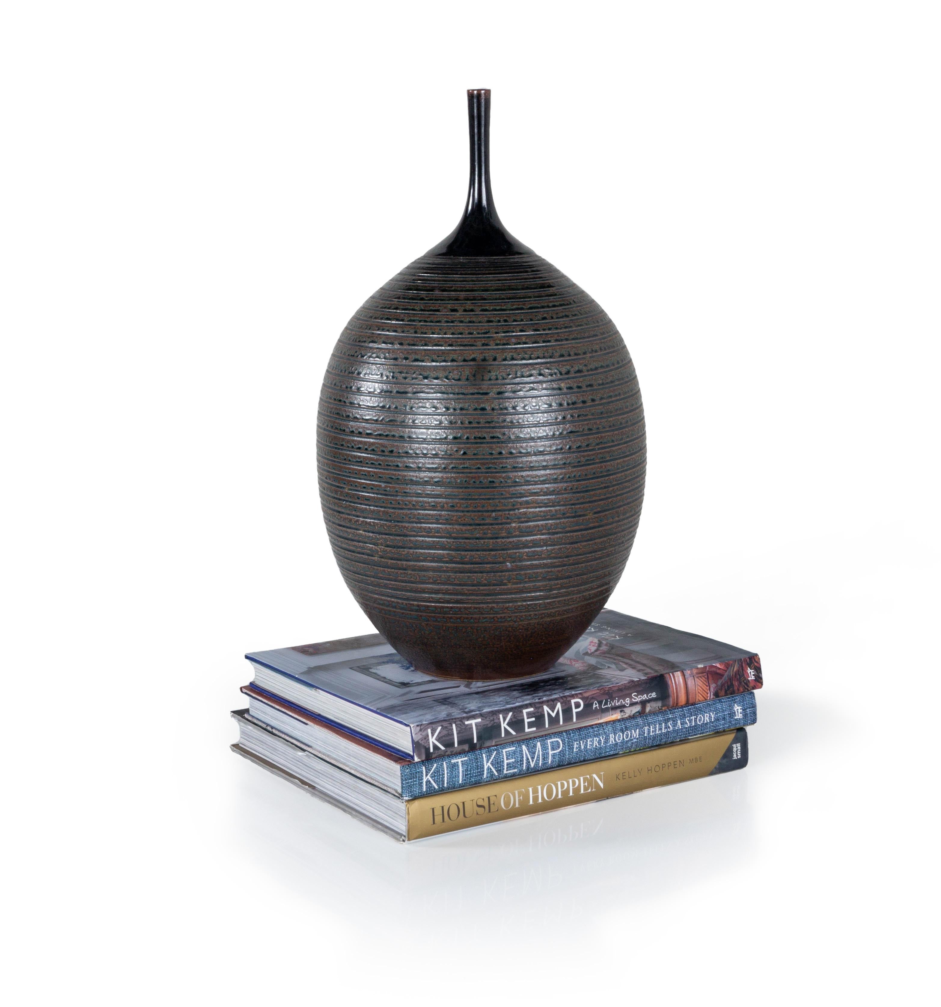 The Vintage Stephen Merritt vase is a beautiful jar and pottery piece from the acclaimed contemporary artist, Stephen Merritt. The vessel is made of high-fired earthenware and has a glazed polish finish with a subtle striped pattern at the top. This