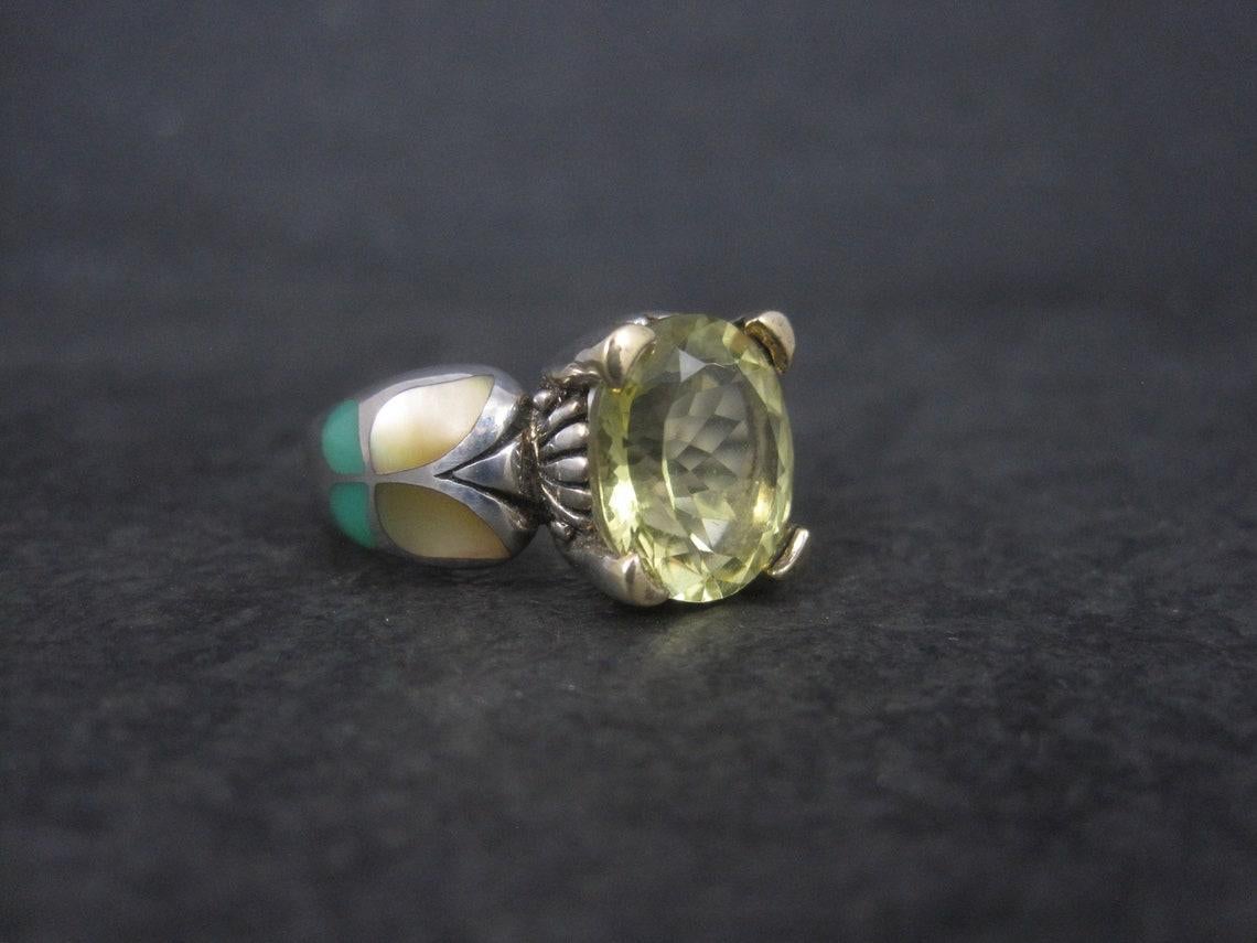 Cette magnifique bague de succession est un produit d'Eric Grossbardt.
Il est en argent sterling et rehaussé d'or jaune 18 carats. Il est orné d'un quartz citron de 10x12 mm et de magnifiques papillons incrustés.

La face de cette bague mesure un