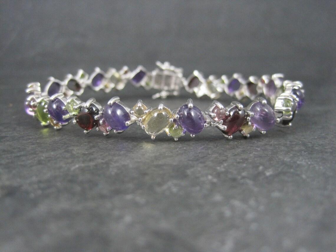 Ce magnifique bracelet de succession est en argent sterling.
Il comprend des grenats, des citrines, des péridots, des améthystes et des tourmalines roses taillés en cabochon.

Dimensions : 3/8 de pouce de large, 7 3/4 pouces portables

Condit :