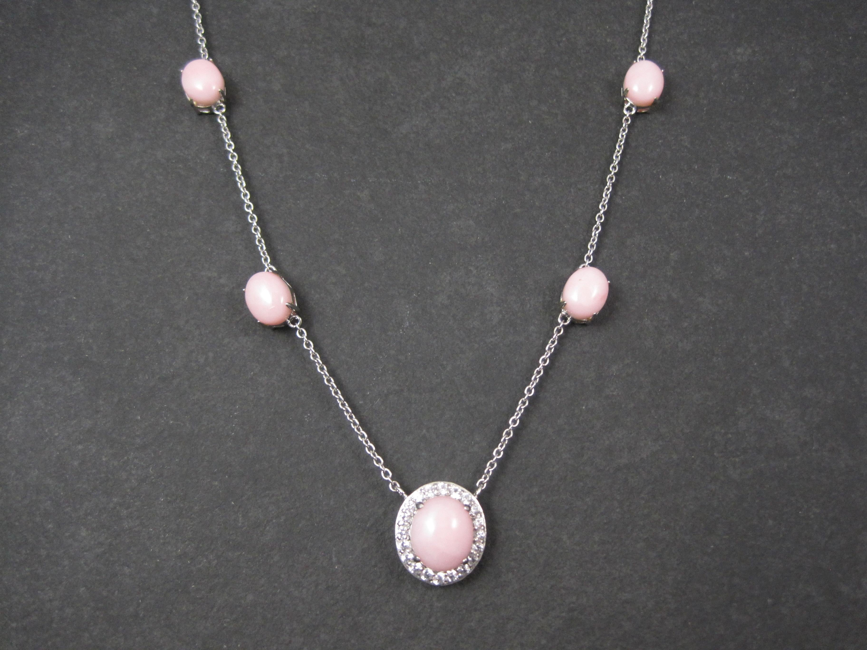 This beautiful 90s necklace is sterling silver with high end pink opal and a halo of white topaz.

The 8 smaller opal cabochons measure 8x10mm. The largest measures 10x12mm.
*Note that one opal is more orange than the others.
The necklace measures