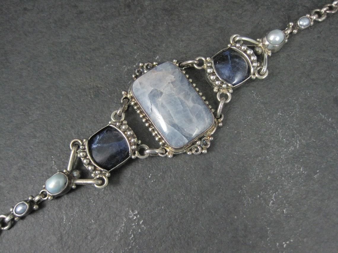 This gorgeous estate bracelet is a product of Sajen.
It features genuine pearls, sodalite and what I believe is quartz.

The face of this bracelet measures 1 9/16 inches wide. The chain measures 1/4 of an inch wide.
The bracelet can be fastened