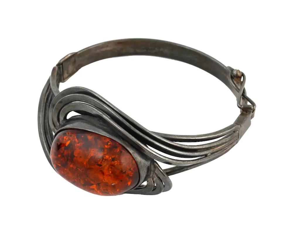 A vintage sterling silver hinged cuff bracelet. The front part has an Art Nouveau curved design and is set with a large oval cognac amber stone. Total Weight: 30 grams. Elegant Statement Jewelry For Women.

Dimensions: D 1 3/4 in. All measurements