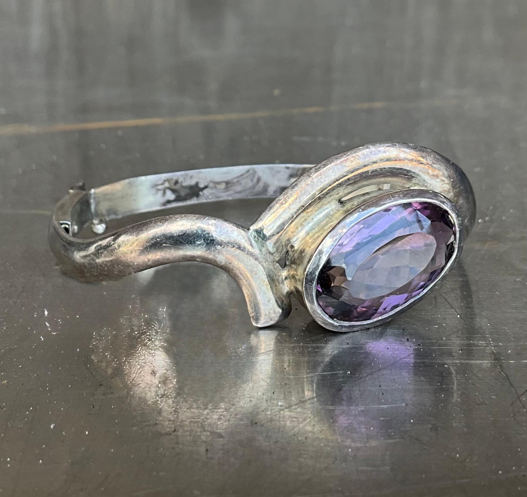A Vintage Sterling Silver Amethyst Cuff is a bold, elegant piece of jewelry that combines the durability and timeless appeal of sterling silver with the rich, vibrant hue of amethyst gemstones. 

This cuff features a wide, open design that wraps