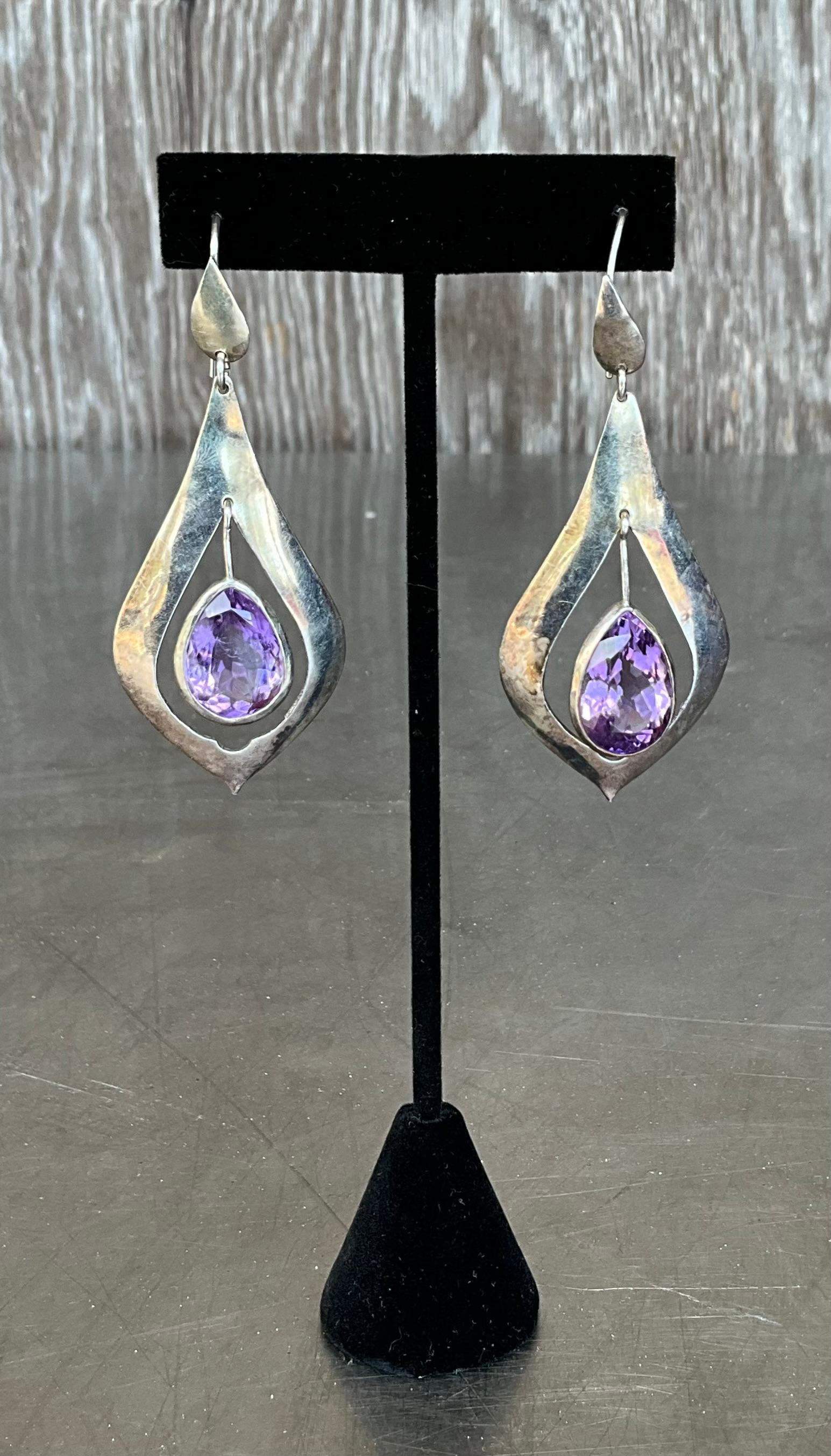 These Vintage Sterling Silver Amethyst Drop Earrings are a timeless and elegant accessory, perfect for adding a touch of sophistication and color to any outfit.

These earrings feature a drop style, where the amethyst stones dangle delicately from a