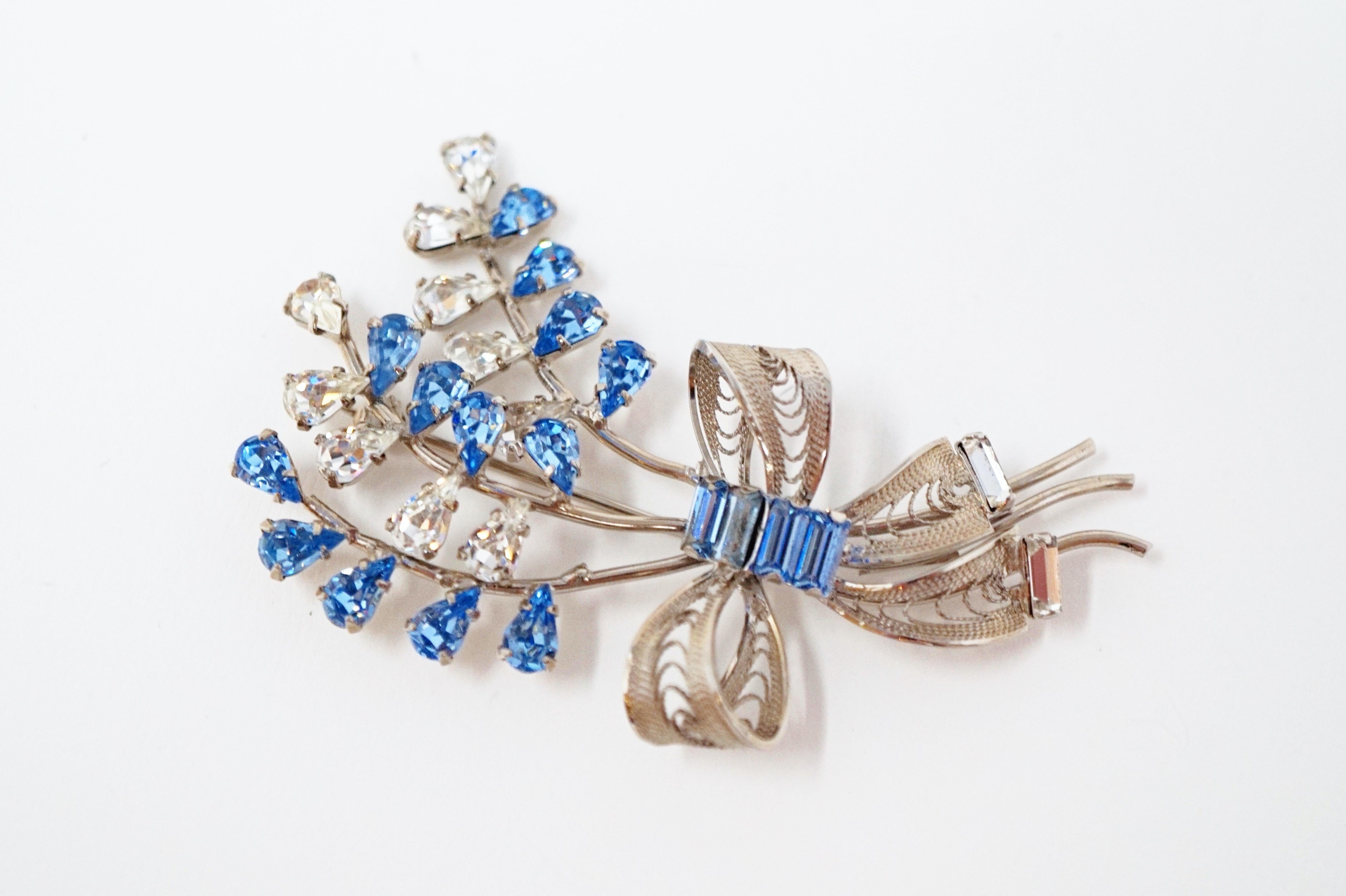 Beautiful vintage sterling silver and rhinestone brooch, circa mid-20th century.  Clear rhinestones alongside cornflower blue colored rhinestones in teardrop and baguette cuts sparkle and shine on this gorgeous piece.  A bow ties this bouquet