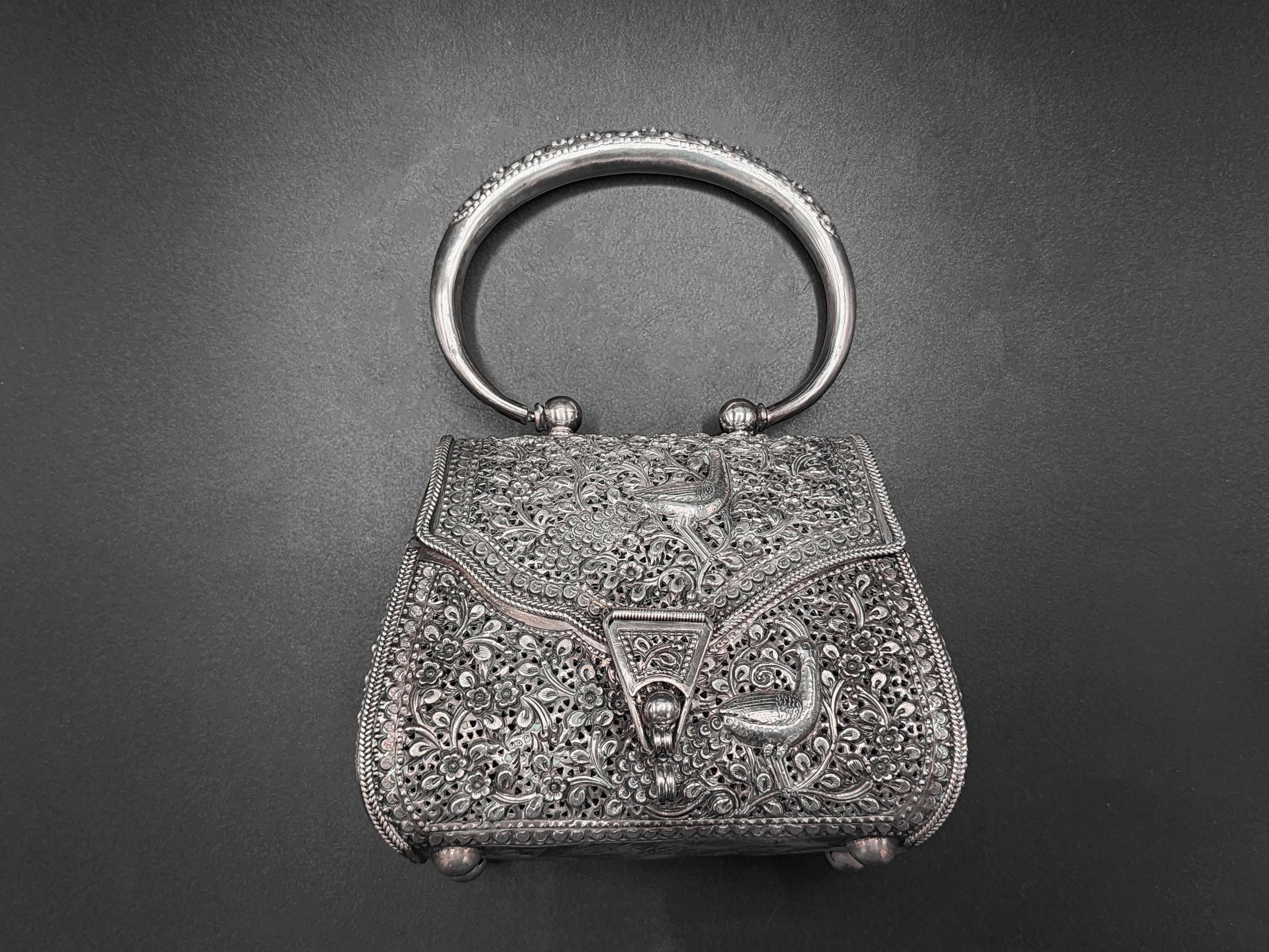 Vintage Sterling Silver Art Nouveau Handbag
Beautiful handbag made of silver with a peacock design on the front and decorated with a pattern of small flowers throughout the design, with a cylindrical handle with the matching detail of the flowers