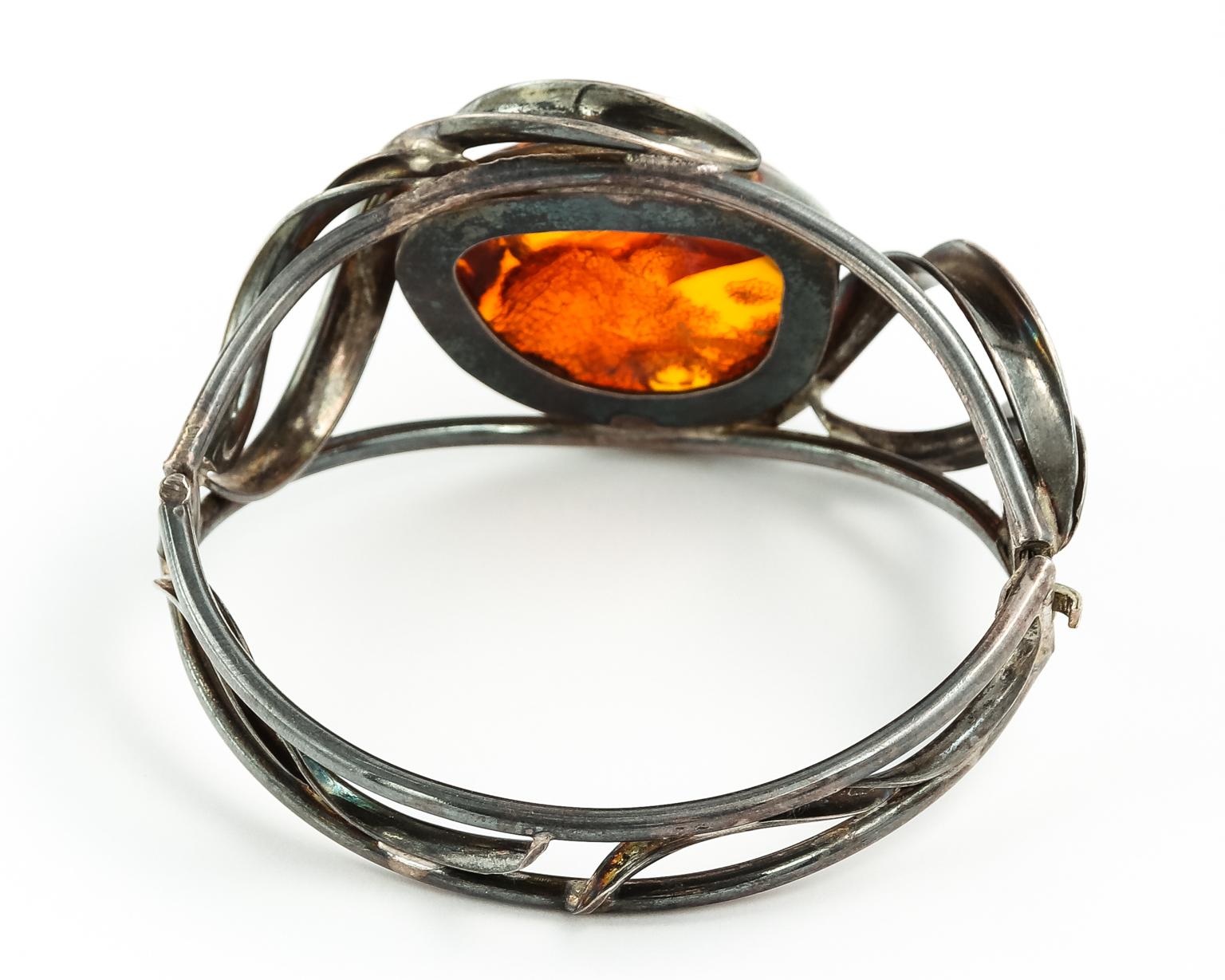 Genuine amber cuff bracelet. It has modern swirly patterns surrounding this huge genuine honey amber stone measures 1 1/4 X 1 inches. There are inclusions inside the stone with a leaf pattern that's rough on the back but shows beautifully on the