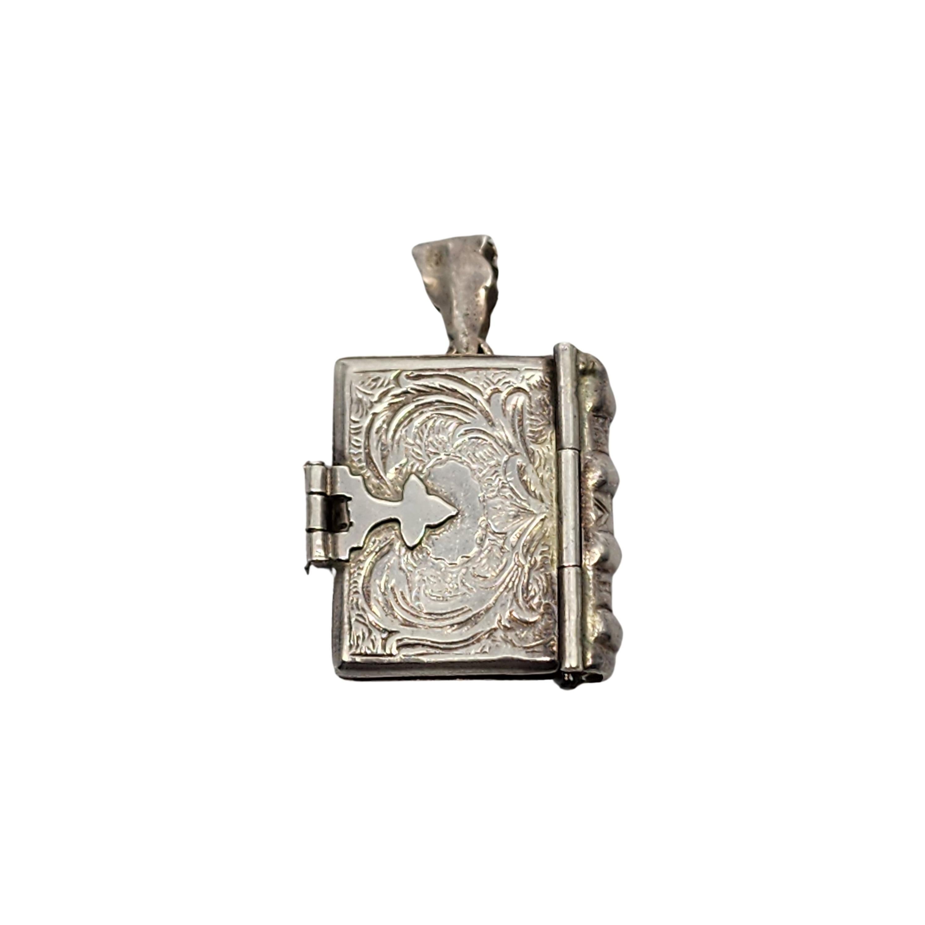 Vintage sterling silver Birmingham import picture book locket, circa 1998.

This locket pendant opens up to hold a photo. Book stays closed with a clasp on the side. Features beautiful etched designs on the front and back covers. It was imported to