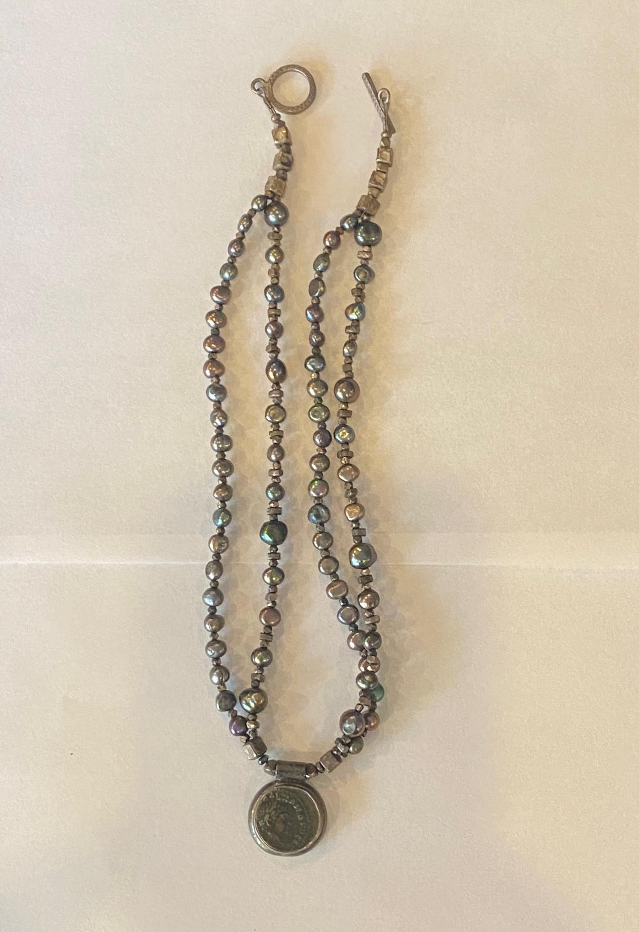 A unique and quite stunning necklace. We haven't seen another quite like it. The piece features a sterling silver design with beads and what appears to be black pearls and a wonderful ancient Roman coin as the necklace's hanging center piece