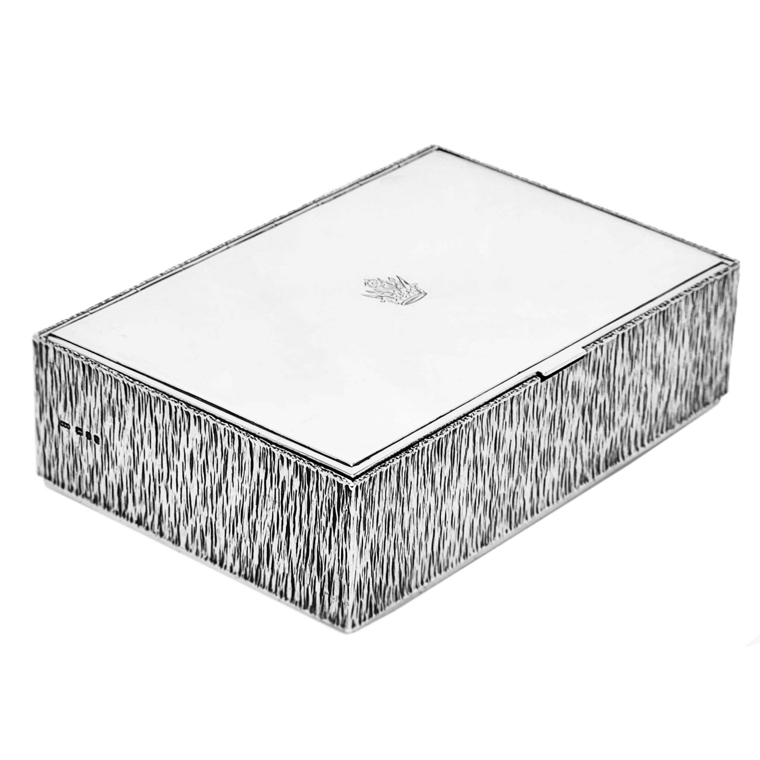 A gorgeous rectangular sterling silver box by Gerald Benney. The Box is embellished with a bark effect on the sides typical of Benney's designs. The lid of the box is plain polished Silver with a small crest engraved in the centre. The interior of