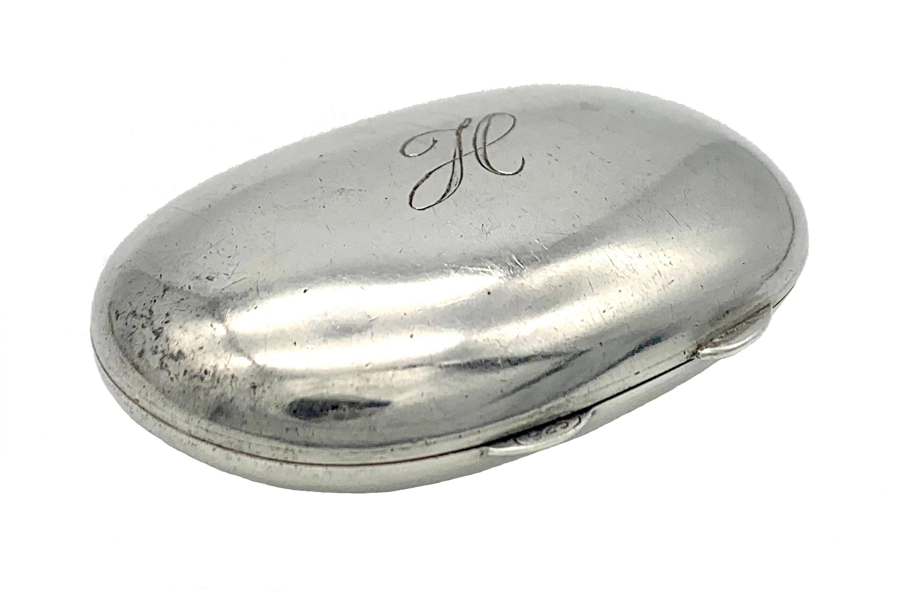 This smooth silver pill box is made out of sterling silver in the second half of the 20th century.  It is a lovely little object to hold in your hands. One of the handles used to open the box is marked 925 within an oval frame. The pill box is